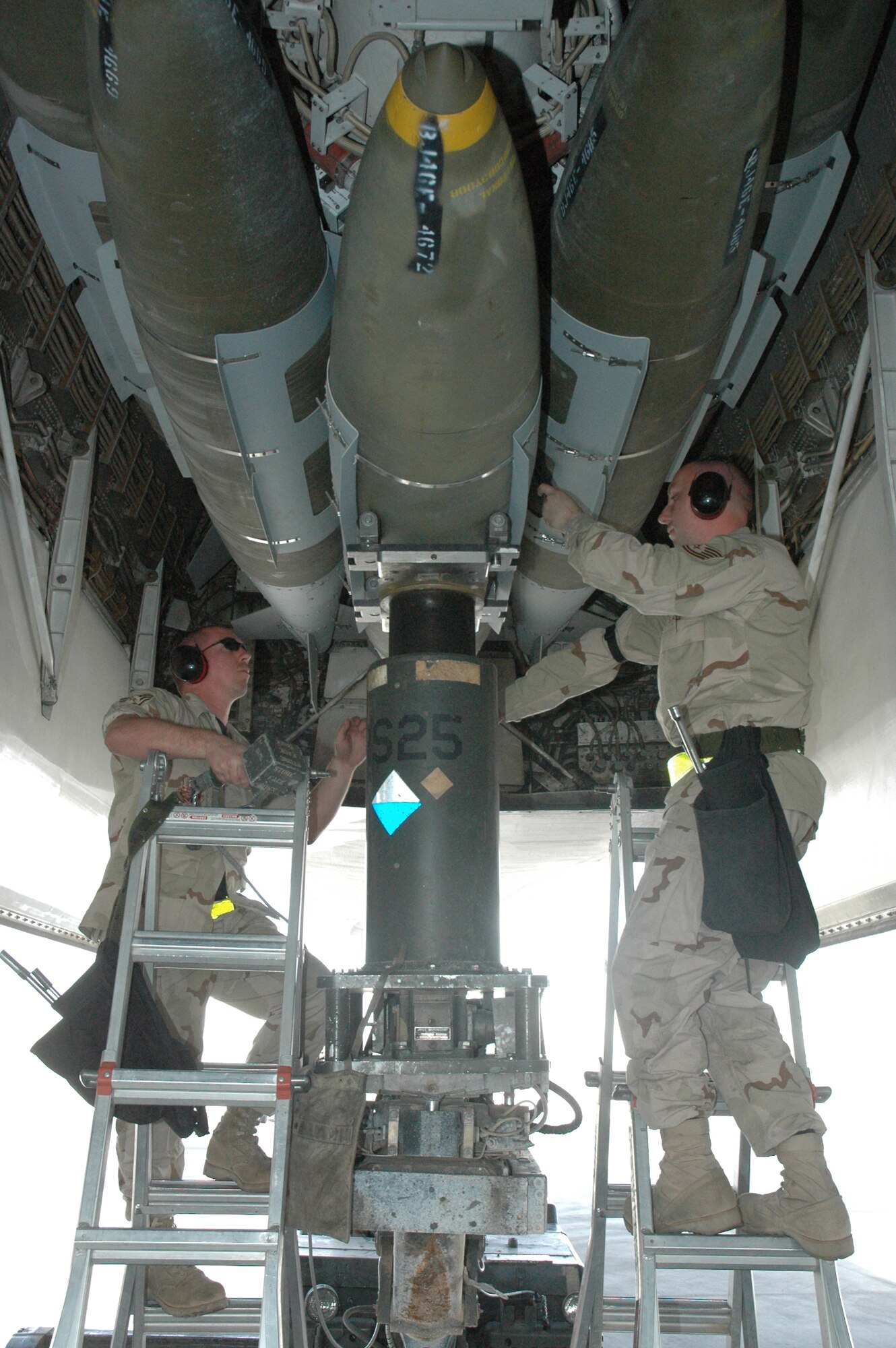 Staff Sgt. Kevin Rayburn (left) and Tech. Sgt. Jeff Allen, 379th EAMXS weapons load crew members load a 2000 pound GBU-31 Joint Direct Attack Munition hoisted up by a MJ-40 lift truck onto a B-1 Wednesday. (U.S. Air Force photo by Senior Airman Erik Hofmeyer)