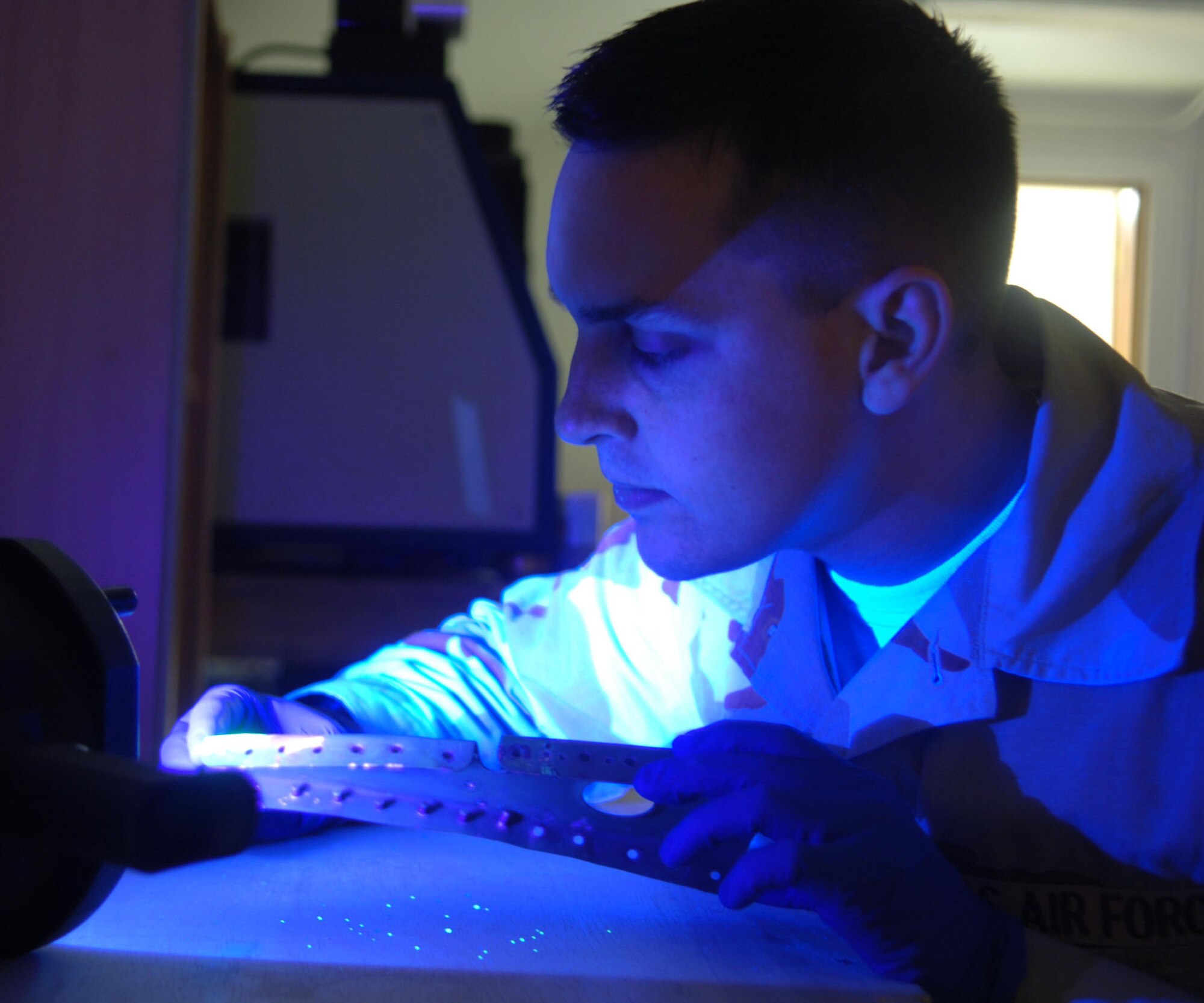 Airman 1st Class Jeffrey Pilgreen of the 455th Expeditionary Maintenance Squadron nondestructive inspection team inspects an aircraft part using an ultraviolet light and a special dye to detect flaws. (U.S. Air Force photo/Staff Sgt. Kevin Tomko)