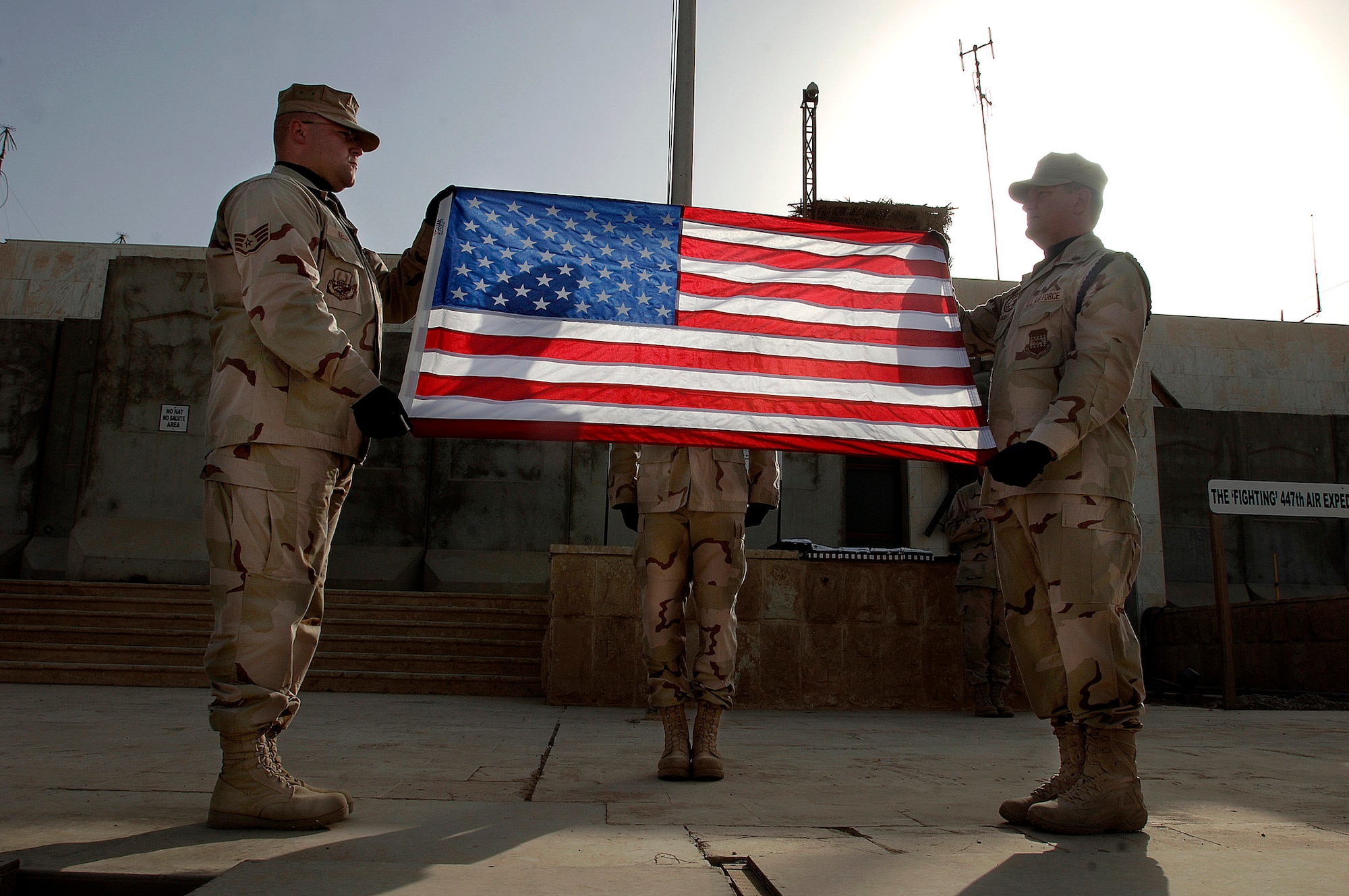 Staff Sgt. Andrew Keller (left) and Maj. Shannon Kolnsberg prepare to fold a U.S. flag as Staff Sgt. Jody Nitz remains at attention during an official flag raising and folding ceremony April 21 in Baghdad, Iraq.  The Sather Air Base Honor Guard raised and folded 23 U. S. flags. The three Airmen are assigned to the 447th Expeditionary Medical Squadron. (U.S. Air Force photo/Tech. Sgt. Cecilio M. Ricardo Jr.)