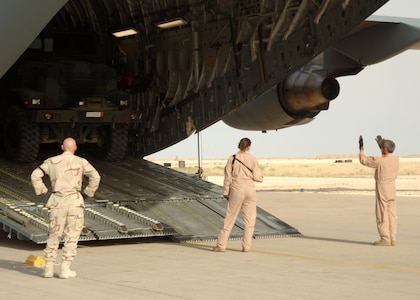 Airmen assigned to the 438th Aerial Port Flight and an aircrew from Charleston Air Force Base, S.C., coordinate the offload of a C-17 Globemaster III April 21 at Al Asad Air Base, Iraq. Since January, 438th APF Airmen have processed more than 32,000 passengers, 15,528 tons of cargo and more than 2,600 aircraft, keeping nearly 12,000 American servicemembers off the roads in convoys. (U.S. Air Force photo/Capt. Ken Hall)