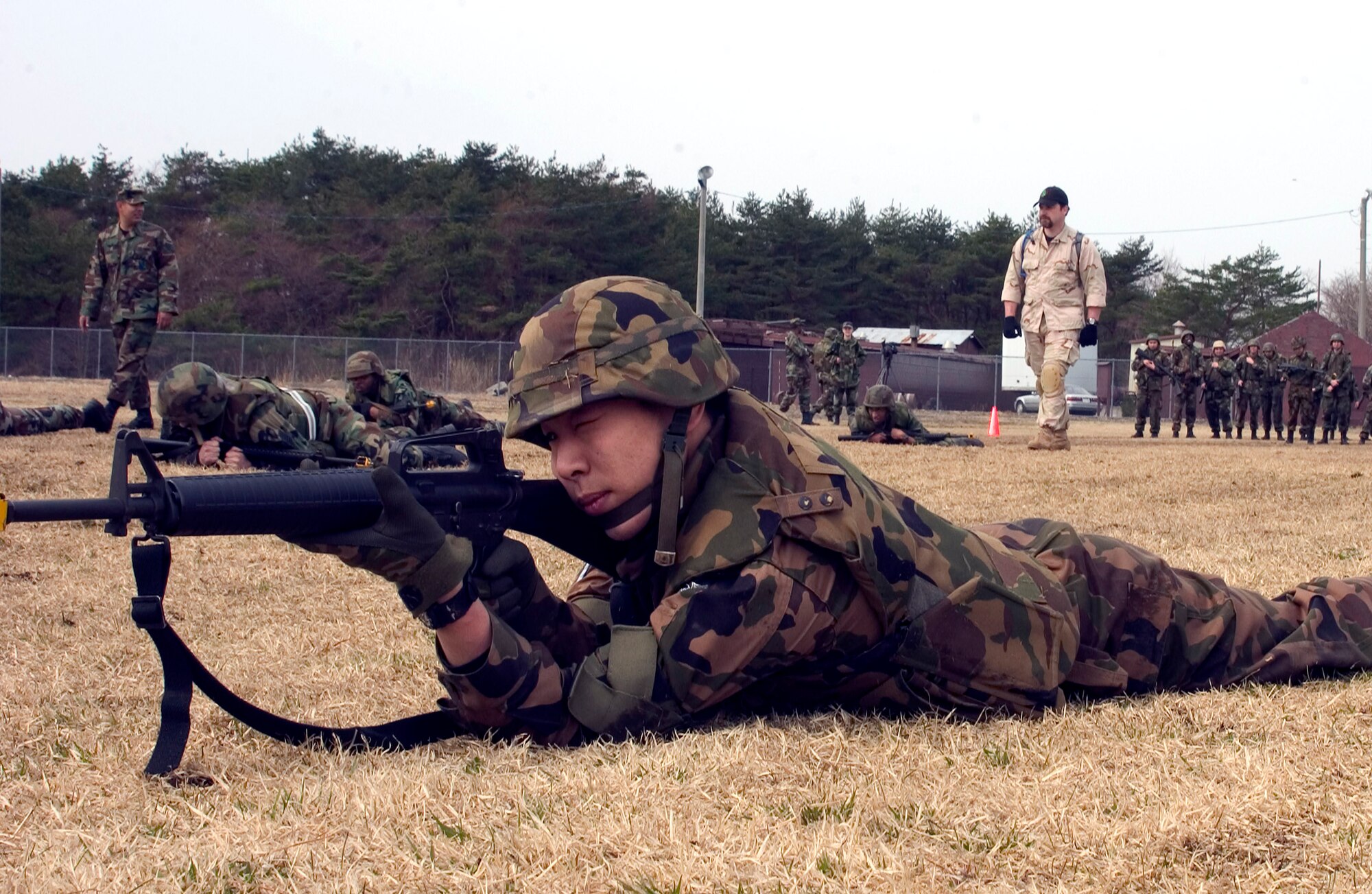 Senior Airman Takao Itoh, a student in the Expeditionary Combat Skills Training, assumes a prone firing position after a high crawl maneuver at Camp Defender on Misawa Air Base, Japan. The ECST course held April 23 to 25 is designed to prepare Airmen for deployment. Airman Itoh is a member of the Japan Air Self-Defense Force. (U.S. Air Force photo/Airman 1st Class Eric Harris) 