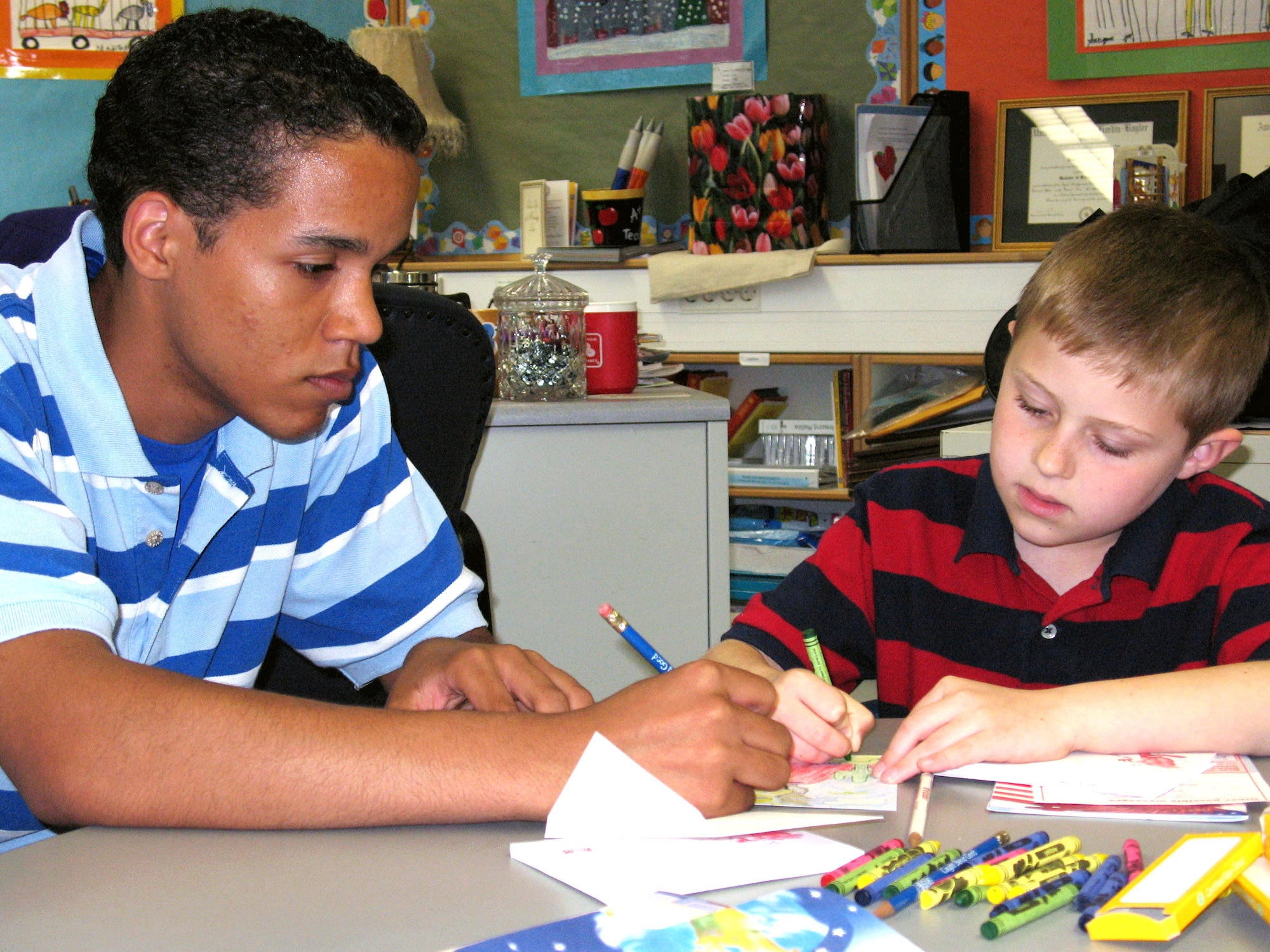 Brice Relaford helps Caleb Parrish draw a card for his father April 26 at Ramstein Air Base, Germany. Brice and Caleb are "Deployment Buddies," which is a program for high school and elementary school students who have parents that have deployed or will deploy. The buddies pair up and spend a day doing activities such as making cards for their parents, dancing the "Hokey Pokey" and playing games. The event happens once a month. Brice is a Ramstein High School junior. (U.S. Air Force photo/Staff Sgt. Leigh Bellinger)
