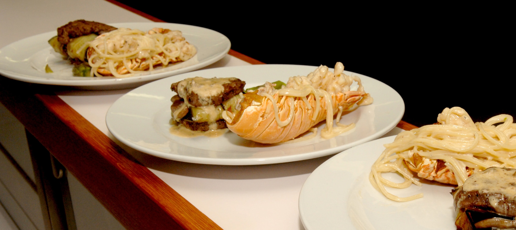 SPANGDAHLEM AIR BASE, GERMANY -- Plates of lobster alfredo and grilled tenderloin prepared by members of the 52nd Services Squadron Mosel Dining Facility staff await judging during a test run of the Iron Chef competition. (US Air Force photo/Senior Airman Josie Kemp).