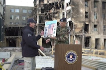 Army Maj. Gen. James T. Jackson presents FBI special agent Arthur Eberhart a poster-sized photo of the American flag unfurled from the roof of the Pentagon Sept. 12, the day after terrorist crashed a hijacked jetliner into the building. Eberhart, special agent in charge of the FBI crime scene investigation at the Pentagon, turned over control of  the site to Jackson's command, the Military District of Washington, in a transfer ceremony Sept 26, 2001.