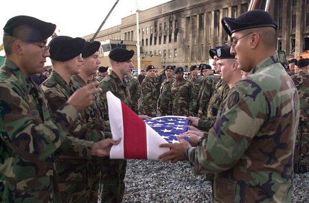 Soldiers of the 3rd U.S. Infantry (The Old Guard) fold an American flag that had been displayed at the Pentagon disaster and recovery site. The FBI transferred site control to the Army's Military District of Washington on Sept. 26, 2001. The flag was a commemorative gift to FBI crime scene investigators, who continue their operations in a nearby parking lot.