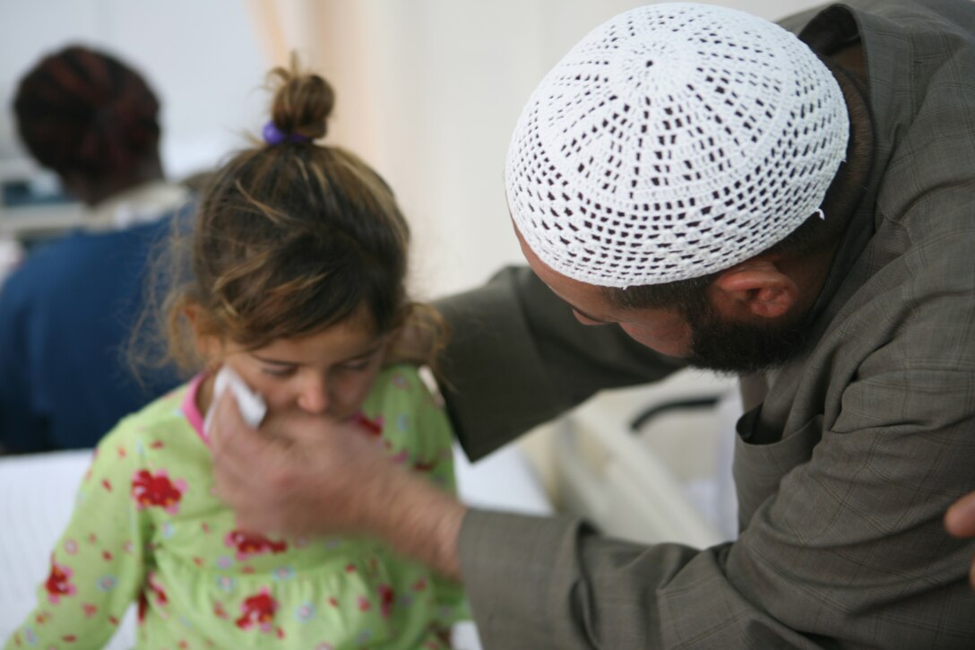 AL ASAD, Iraq- Adel Khalil Abdulla wipes the tears off his daughter Nehad's face, May 2.  Nehad was injured by shrapnel during a terrorist attack while playing soccer outside of her house on April 25.