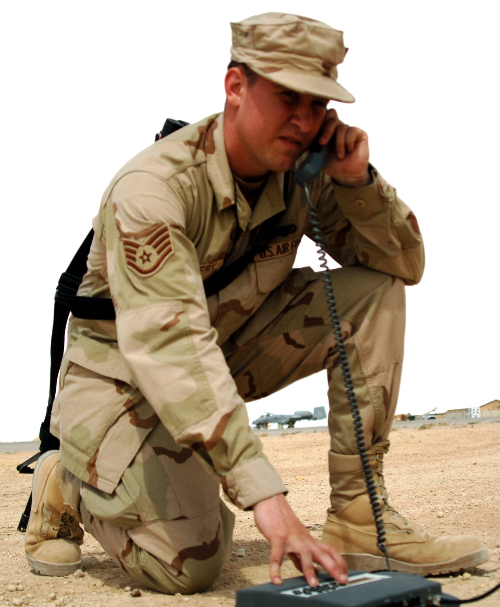 Staff Sgt. Sean Mallery operates an international maritime satellite phone while one of the group's A-10 Thunderbolt IIs is preflighted in the background before a combat mission over Al Anbar Province. He deployed from the 47th Communications Squadron at Laughlin AFB, Texas, and is assigned to the 438th Air Expeditionary Group at Al Asad Air Base, Iraq. (U.S. Air Force photo/Capt. Ken Hall) 
