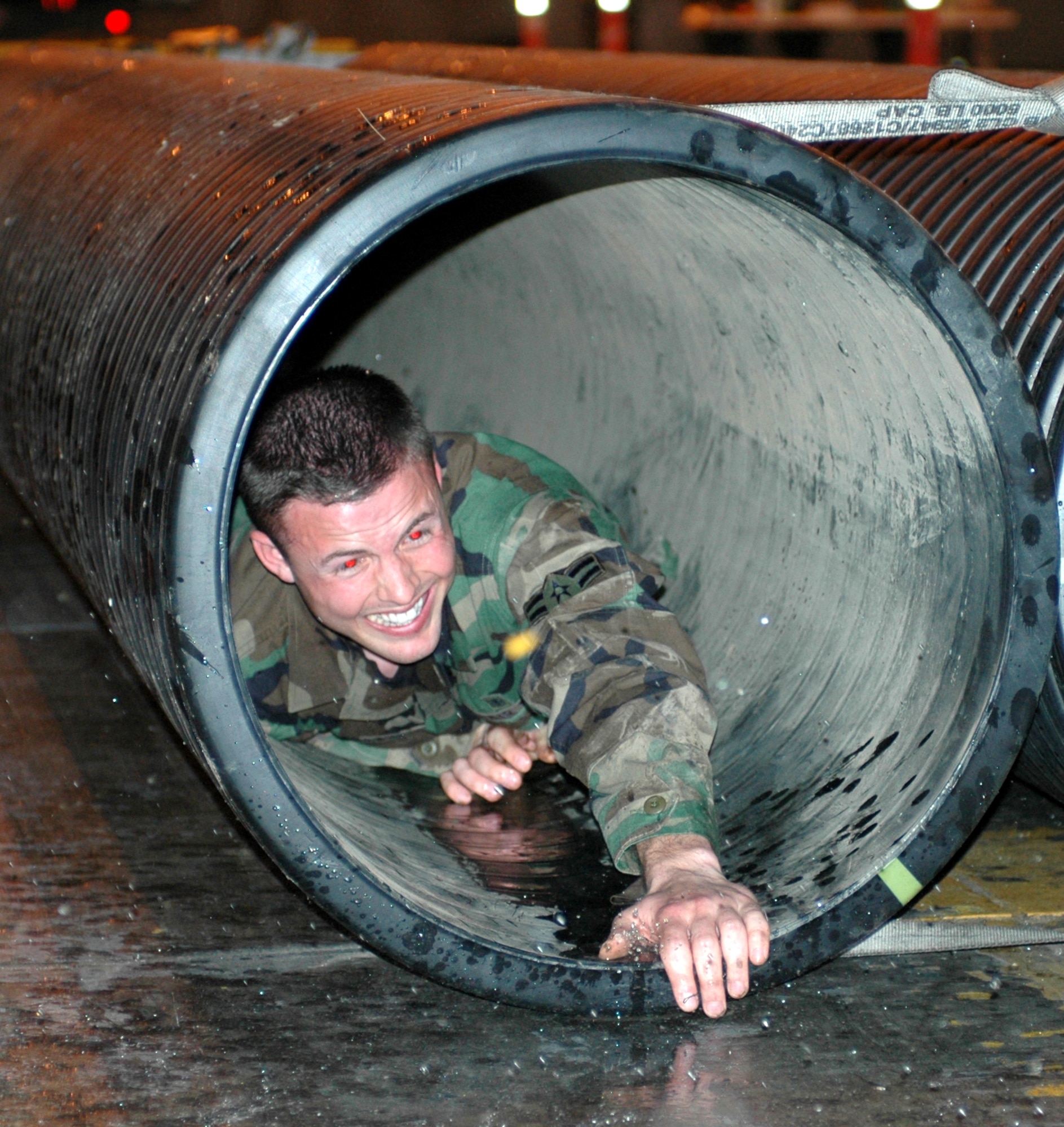 Airman 1st Class Ryan Gleason, 60th Dental Squadron, crawls toward the obstacle course finish line during the Enlisted Combat Dining-In April 27. Airman Gleason was “convicted” of “attempted smuggling.” Airmen “convicted of breaking the rules of engagement” were sent to the Grog via an obstacle course.  (U.S. Air Force photo by Tech. Sgt. Donald Osborn) 