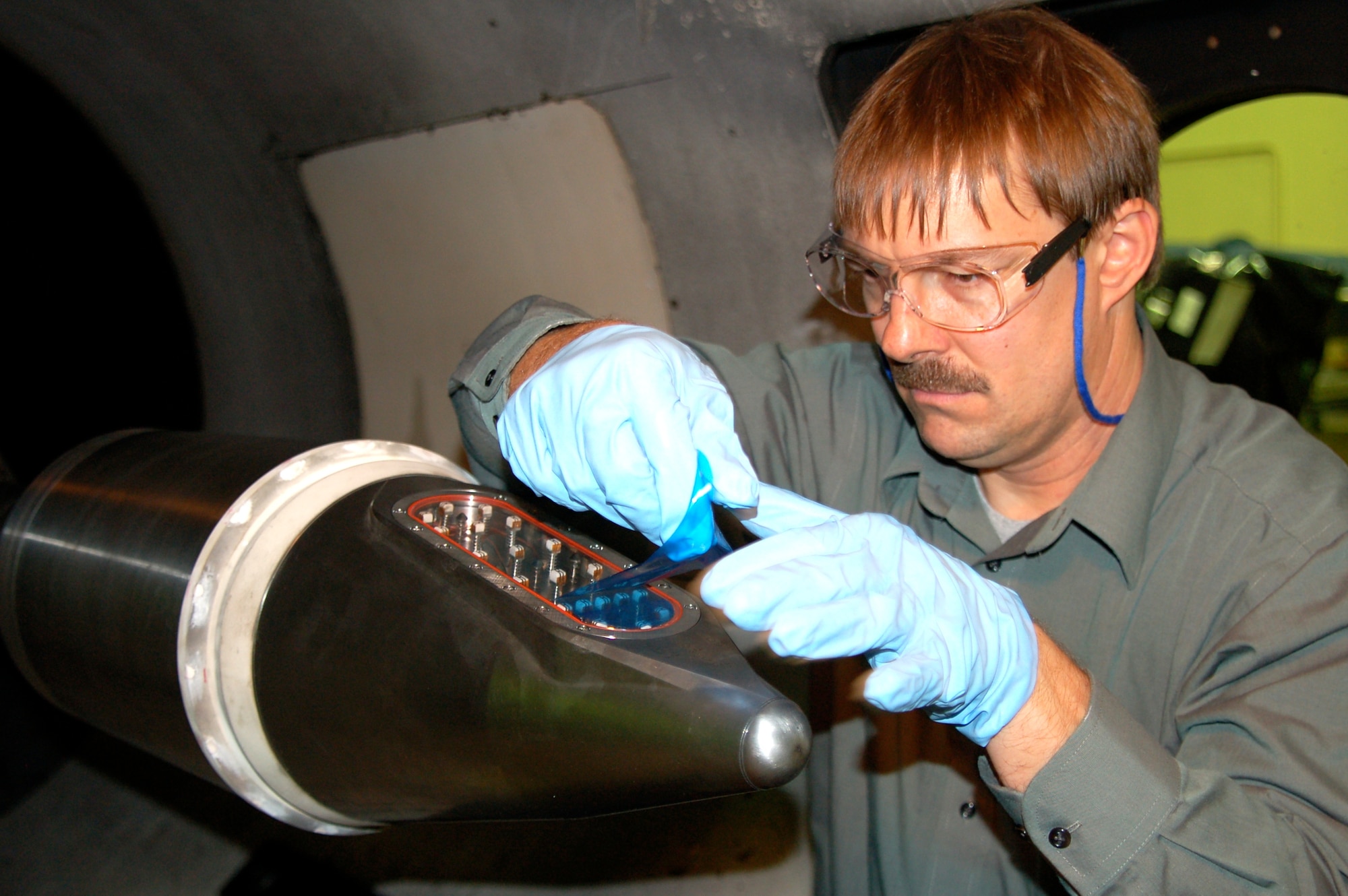 Ladd Henneman, a Lockheed Martin flight sciences engineer, removes a protective film from a Terminal High Altitude Area Defense missile forecone’s infrared seeker window prior to an aerothermal test at Arnold Engineering Development Center’s Hypervelocity Wind Tunnel 9 facility in Silver Spring, Md. The window is made from a new advanced material that will provide improved seeker performance at reduced cost. (Photo by Arnold Collier)