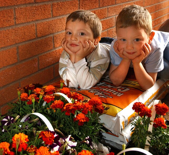 Gabriel Smith , left, 3, and David Pittman , 4, both RAF Mildenhall family members take a break and pose for the camera while planting flowers beds at the RAF Mildenhall Child Development Center April 26. (U.S. Air Force photo by Staff Sgt. Tyrona Pearsall)                                   