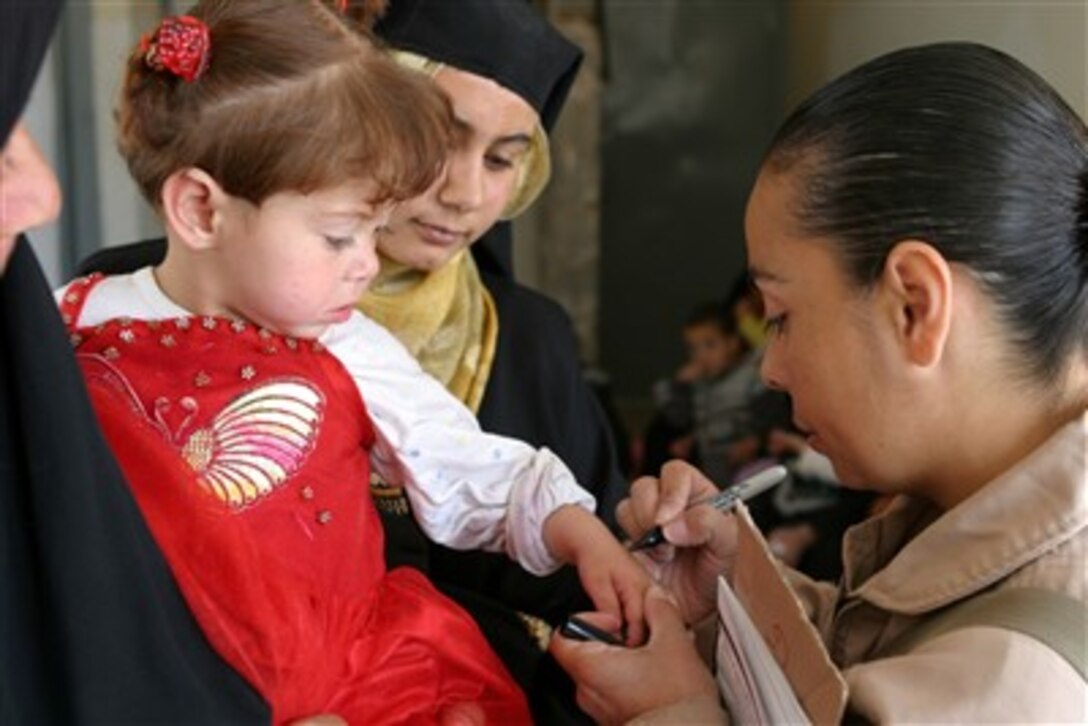 U.S. Marine Corps Gunnery Sgt. Juana Hamlett marks an Iraqi girl's hand to indicate she has already been seen by the medical staff during a combined medical assistance program with Iraqi forces in Habiniyah, Iraq, on April 21, 2007.  Hamlett is assigned to the II Marine Expeditionary Force's communications detachment.  