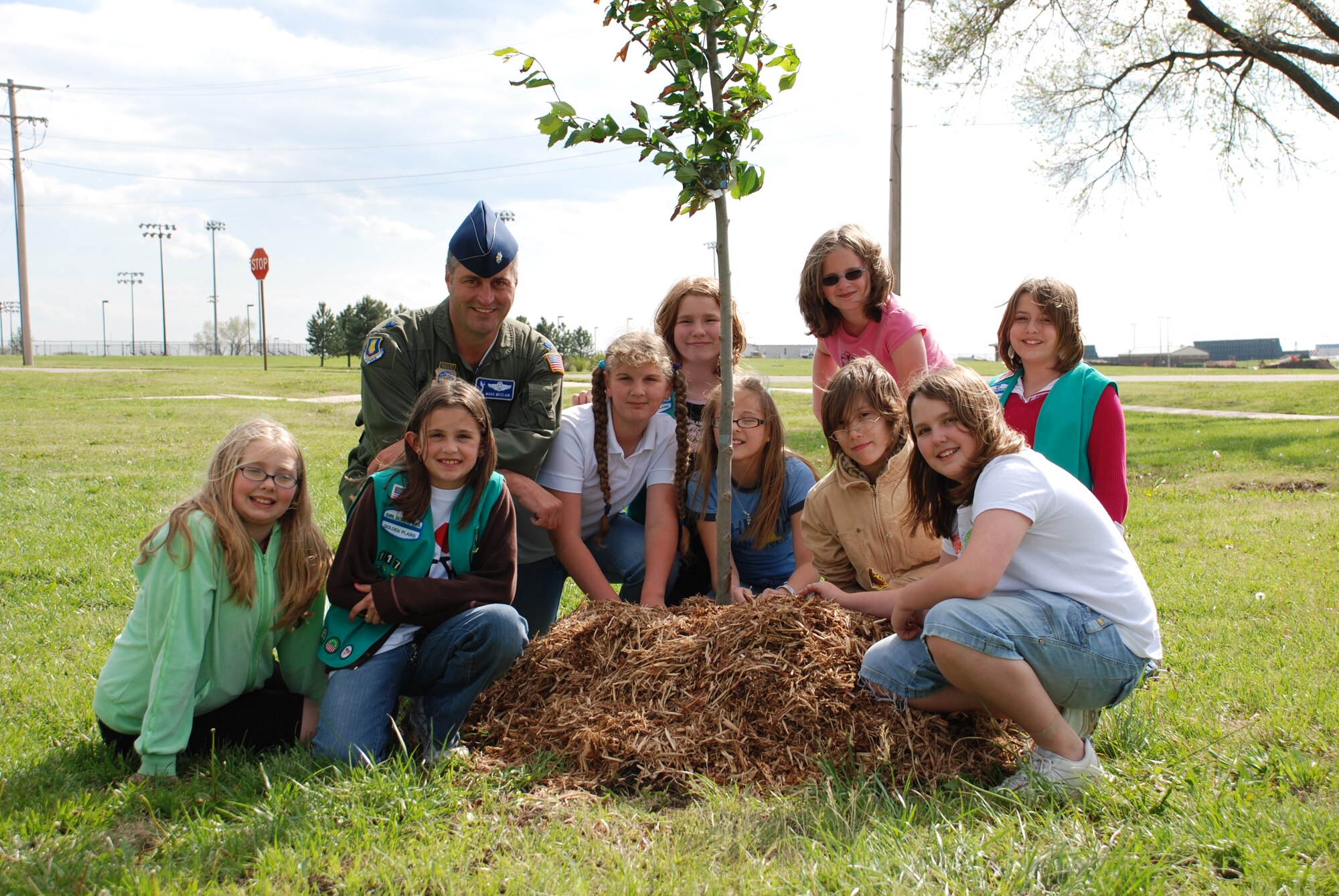 Lt. Col. Mark McClain, 22nd Air Refueling Wing Director of Staff, kneels in front a freshly planted tree with Girl Scout Troop 117, from Wineteer Elementary, to celebrate Arbor Day April 27 here. The troop planted several trees near outdoor recreation with the goal of beautifying McConnell with more landscape. (Photo by Airman 1st Class Jessica Lockoski 22nd ARW Public Affaris)