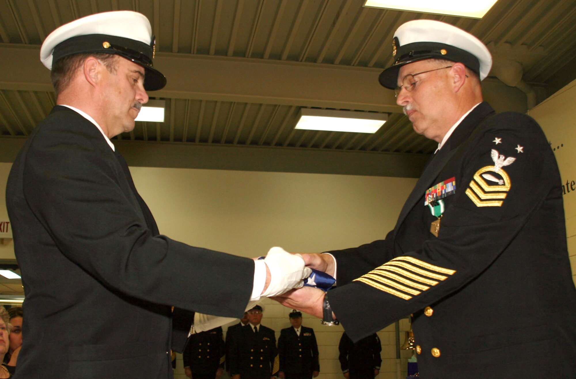 NAVY OPERATIONAL SUPPORT CENTER, Kan. -- Retired Navy Master Chief Petty Officer Randy Pierce, presents a folded American flag to Master Chief Petty Officer Ricke Whiteside during his retirement ceremony held at Navy Operational Support Center, Wichita. Chief Whiteside retired after completing 30 years of naval service. Chief Whiteside currently resides in El Dorado, Kan., and is employed by the El Dorado Fire Department as a fire captain. (Navy photo by Petty Officer 2nd Class Ron Trevino)


