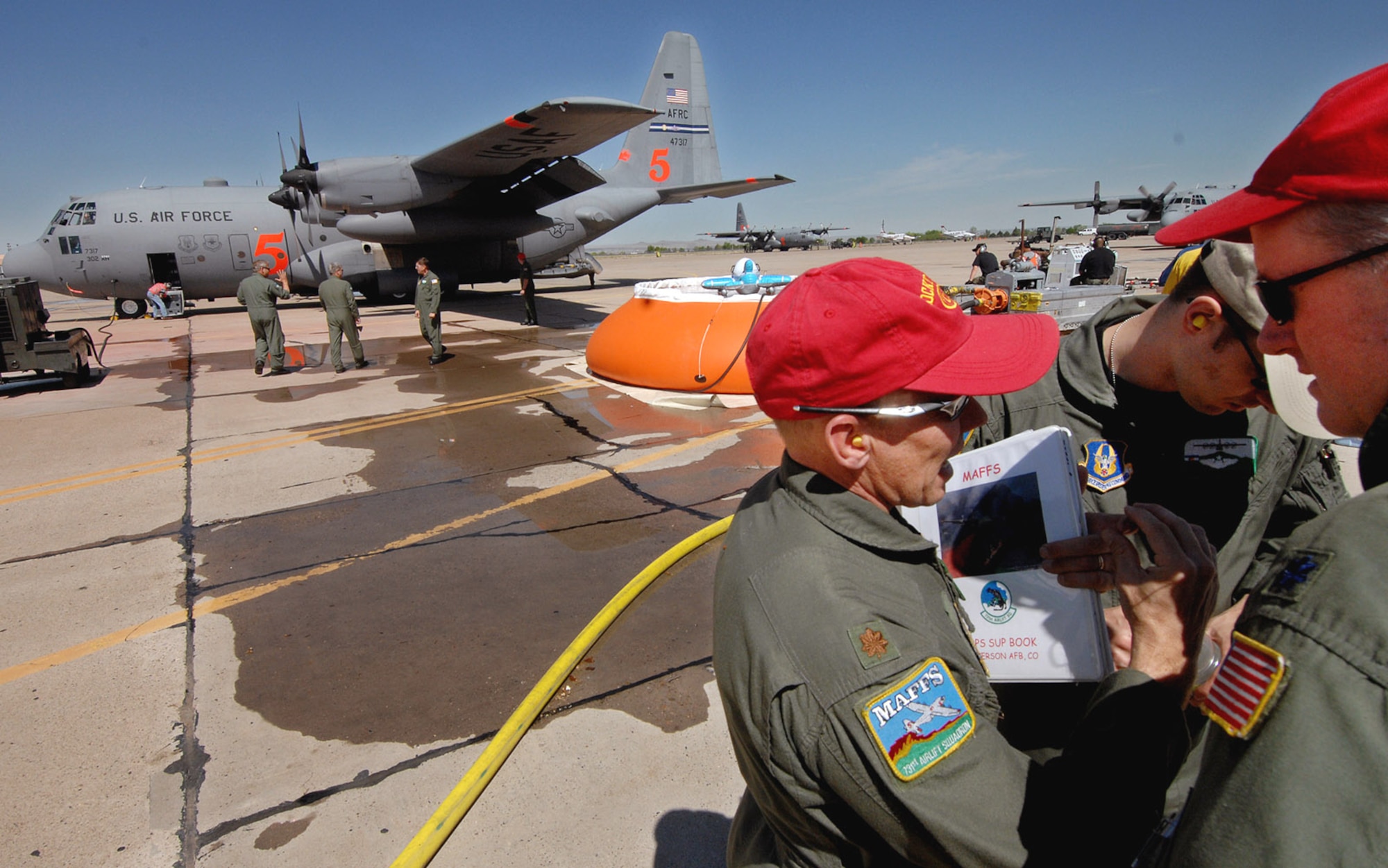 Maj. Mark Steward, left, speaks with Maj. Robert Fairbanks and Lt. Col. Gary Carlton as C-130 Hercules aircraft are prepared to fly Modular Airborne Fire Fighting System training missions May 1 over New Mexico. These C-130 aircrew members from Air Force Reserve Command's 302nd Airlift Wing at Peterson Air Force Base, Colo., as well as other Air National Guard and Air Force Reserve crew members trained at the U.S. Forest Service's Albuquerque Air Tanker Base in New Mexico. (U..S. Air Force photo/Tech. Sgt. Rick Sforza)
