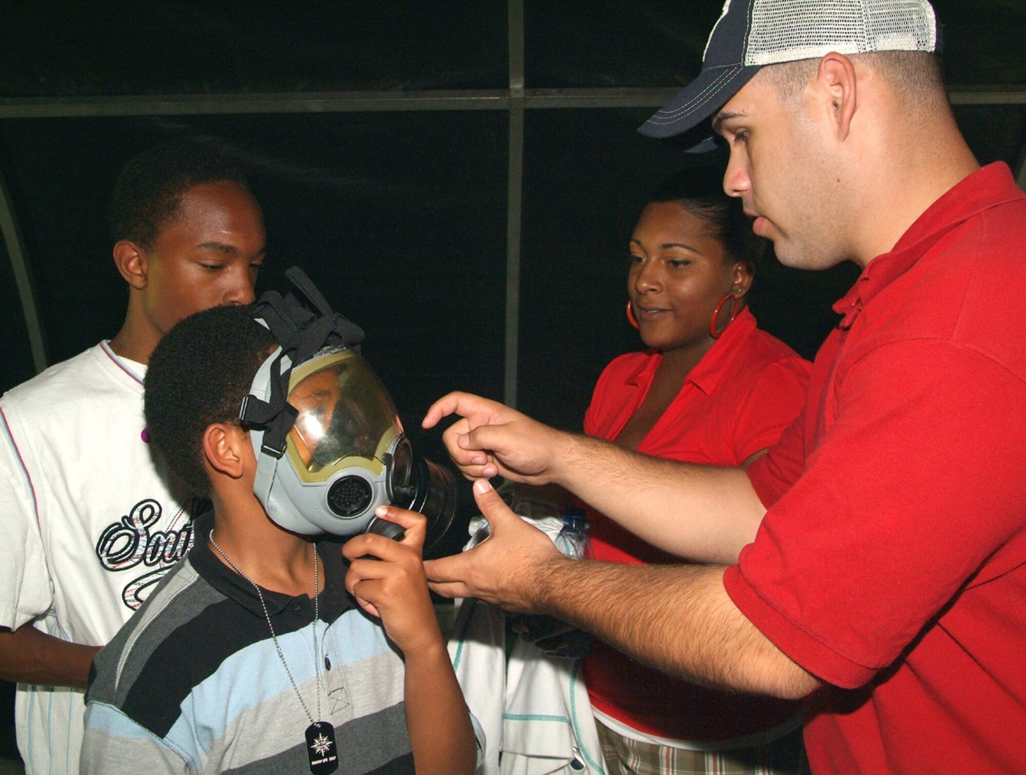 From left, Clayshawn Deramus, 13, waits for his turn trying on the gas mask 9-year-old Christopher Weary practices breathing through as his mom,  Staff Sgt. Tasha Weary, 81st Mission Support Squadron, watches.  Staff Sgt. James LaBelle, 81st MSS, helps to ensure the mask fits correctly.  (U.S. Air Force photo by Adam Bond)