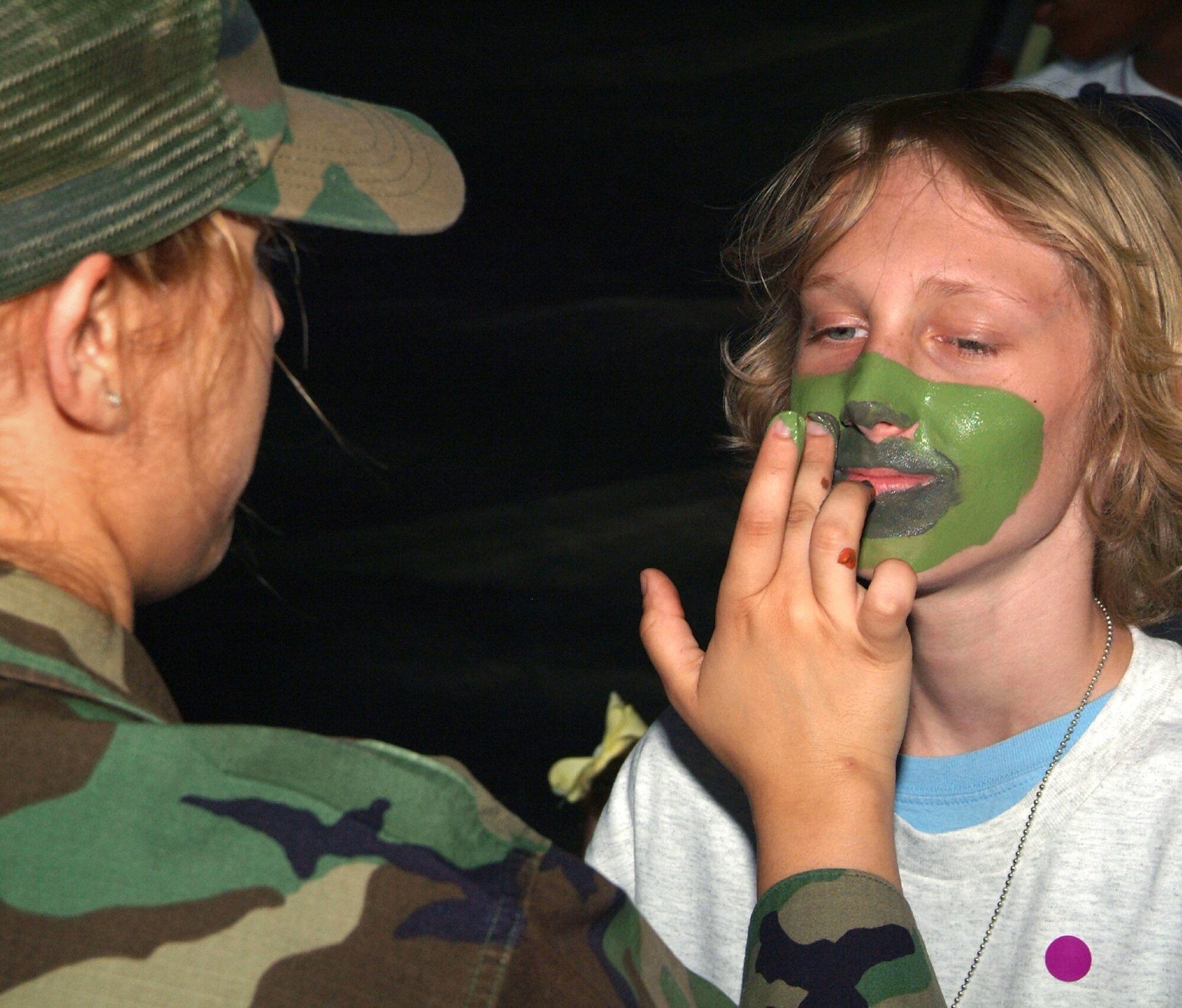 Airman Jounel Caceres, a chaplain’s assistant, applies camouflage paint to the face of Dustin Vineyard, 13, at the deployment facility Saturday during Operation Hero.  Dustin’s parents are Master Sgt. Chad andStaff Sgt.  Casie Vineyard, 81st Training Support Squadron and 403rd Wing, respectively.  (U.S. Air Force photo by Adam Bond)
