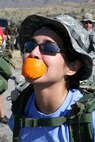 Sgt. Rachell Rozas, 314th Military Intelligence Battalion, quickly crams an orange into her mouth for a boost of energy during the memorial march on March 25 at White Sands Missile Range, N.M. There were several places along the trail that offered bits of bananas, oranges, water or Gatorade. These rest stops helped increase the moral of those walking along.  (USAF photo by Army Spc. Tim Luukkonen)