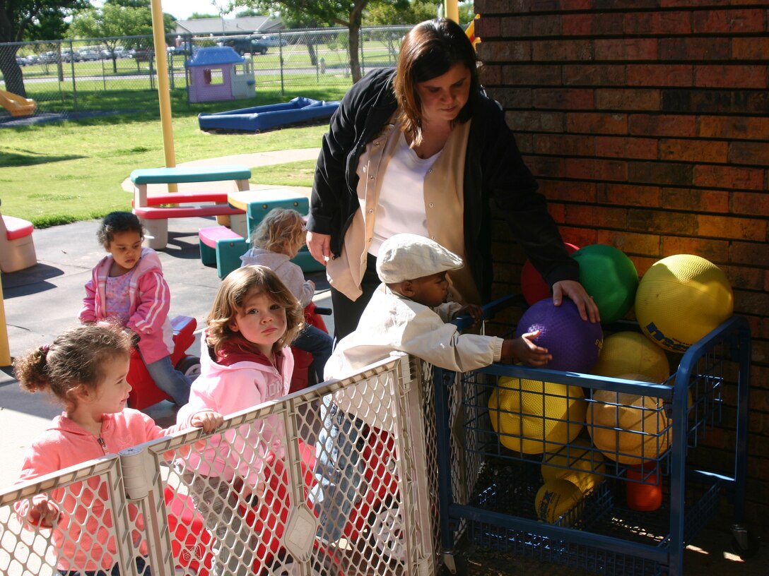 Helen Farson helps one of the toddlers from Room 2AA reach a ball during playtime at the Child Development Center. (U.S. Air Force photo/Staff Sgt. Tonnette Thompson)