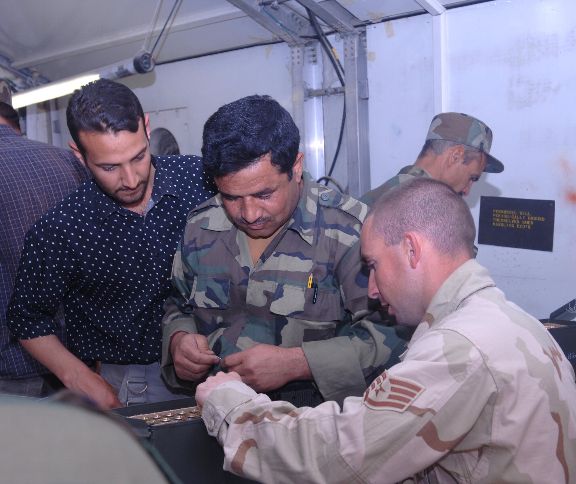 Staff Sgt. Edward Stottlemyer of the 455th Expeditionary Maintenance Squadron instructs a member of the Afghan National Army air corps on arming flares as an intepreter looks on. (U.S. Air Force photo/Staff Sgt. Kevin Tomko)