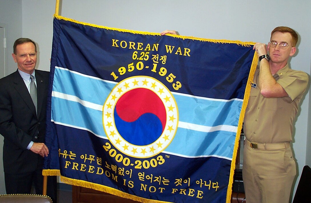 Retired Air Force Maj. Gen. Nels Running (left) and Navy Lt. Cmdr. Jeffrey Bender hold the Korean War Commemoration Community flag at their Crystal City, Va. office. Photo by Jim Garamone.