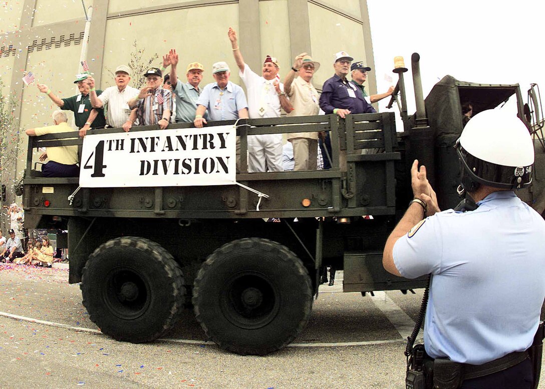 A New Orleans police officer applauds as World War II vets of the 4th Infantry Division pass in the military parade marking the grand opening of the National D-Day Museum in New Orleans. The June 6 celebration coincided with the 56th anniversary of the Allies' invasion of Normandy during the war. Surviving veterans were honored and rode in vehicles dedicated to the major U.S. invasion units. The 4th Division stormed and captured Utah Beach on D-Day. Photo by Bill Cook, DoD. 