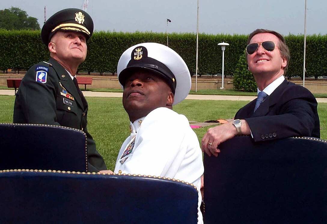 Chairman of the Joint Chiefs of Staff Army Gen. Henry H. Shelton (left) Navy Senior Master Chief Petty Officer Chris Penton (center), and Defense Secretary William S. Cohen watch 12 Army Golden Knight paratroopers perform over the Pentagon River Parade Field during a May 18 full honors armed forces review celebrating the 50th anniversary of Armed Forces Day. Photo by Linda D. Kozaryn 