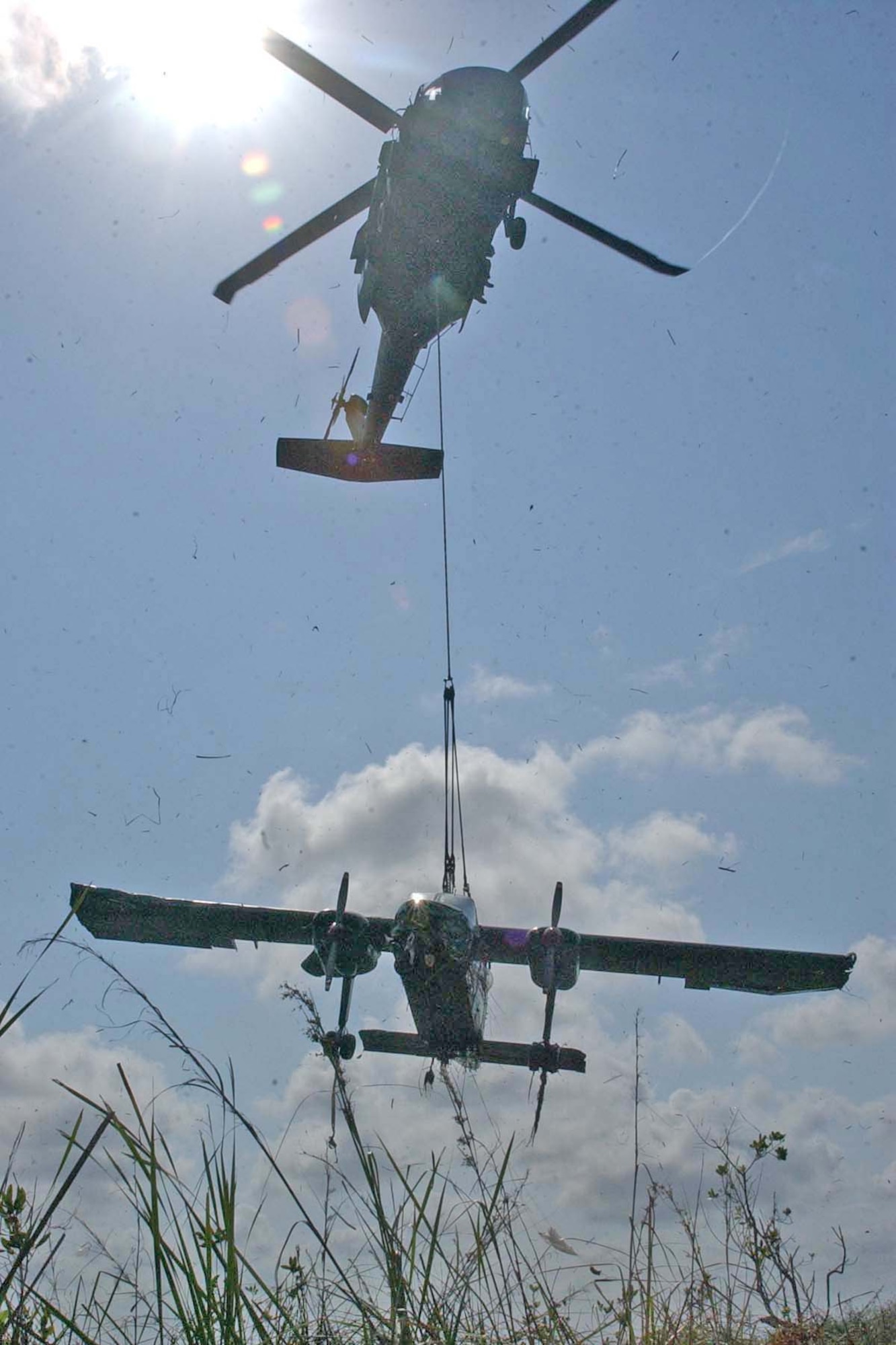 BELIZE CITY, BELIZE -- A United States Army UH-60 Black Hawk helicopter lifted a Belize Defence Force BN-2B Defender aircraft out of the mud near the coast of Belize May 3. Debris flew through the air as the 5,000-pound aircraft was lifted out of the marshes and back to the BDF air station in Belize City. (U.S. Air Force photo by Staff Sgt. Chyenne A. Griffin)                         