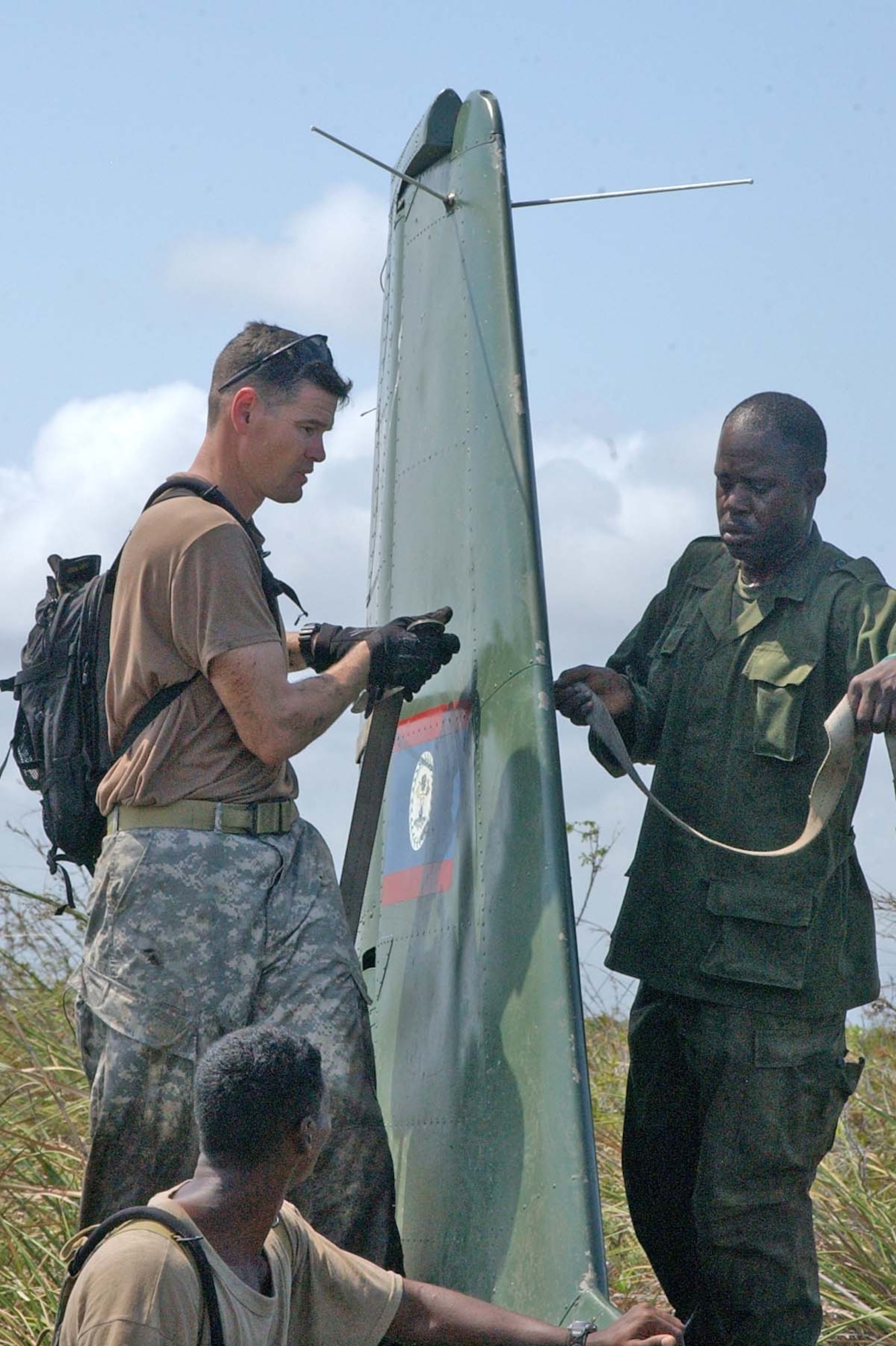 BELIZE CITY, BELIZE -- U.S. Army Sgt. 1st Class Mike Parks, 1st Battalion, 228th Aviation Regiment quality control noncommissioned officer in charge, and a soldier from the Belize Defence Force cargo strap the rudder of a downed BDF Defender aircraft. The downed BDF Defender aircraft was successfully slingloaded onto a U.S. Army UH-60 Black Hawk helicopter and delivered to the BDF air station at Belize City International Airport May 3. (U.S. Air Force photo by Staff Sgt. Chyenne A. Griffin)                                  