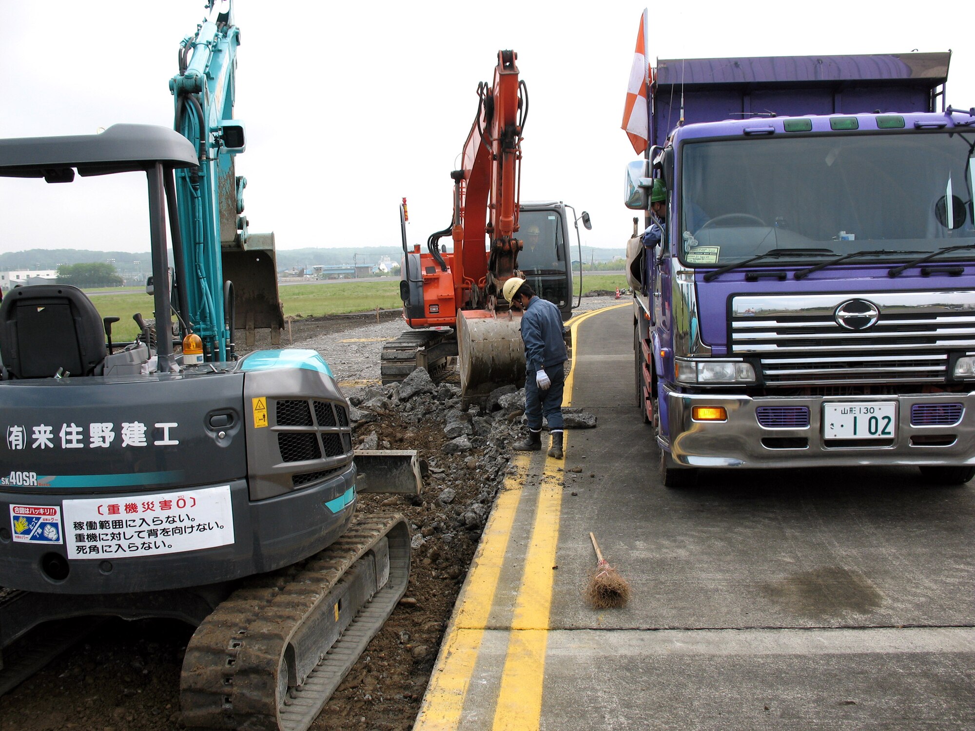 Japanese contractors work together to tear apart chunks of Yokota Air Base flightline's northwest shoulder and taxiway in preparations to repave it. Constant upkeep of the flightline is imperative to keep the base mission-ready. (U.S. Navy photo/Petty Officer 3rd Class Jason Segedy)