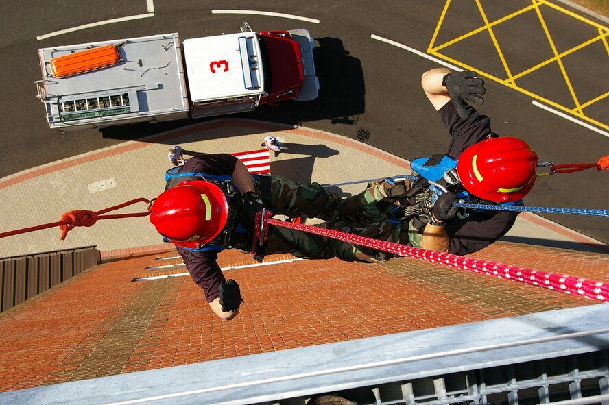 Col. Mike Callis, 100th Air Refueling Wing vice commander, left, performs a reenlistment with Master Sgt. Mark Annis, 100th Civil Engineer Squadron Fire Department, while rappelling down the side of the air traffic control tower at RAF Mildenhall May 2. (U.S. Air Force photo by Karen Abeyasekere)