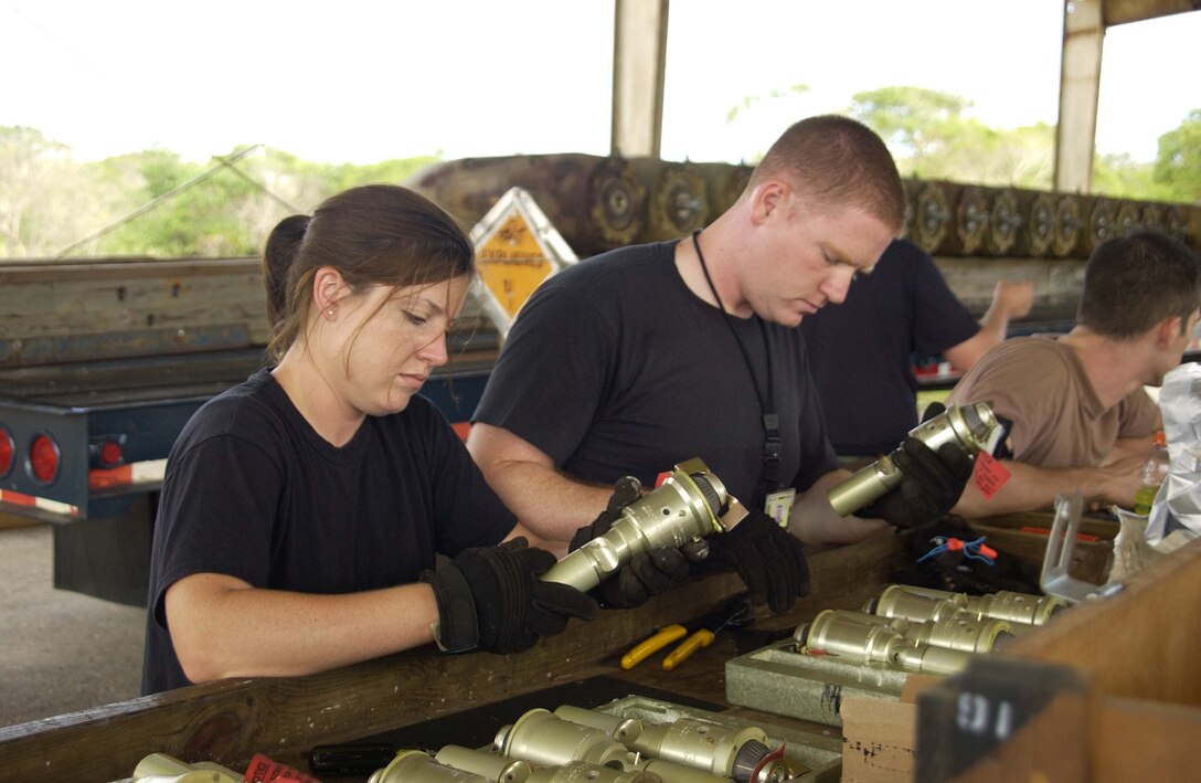 Senior Airman Melissa Marett and Staff Sgt Stephen Hurt, 36th Munitions Squadron, check for minor pitting and corrosion on bomb fuses.  (Photo by Senior Master Sgt. Don Perrien/ 36th Operations Group)