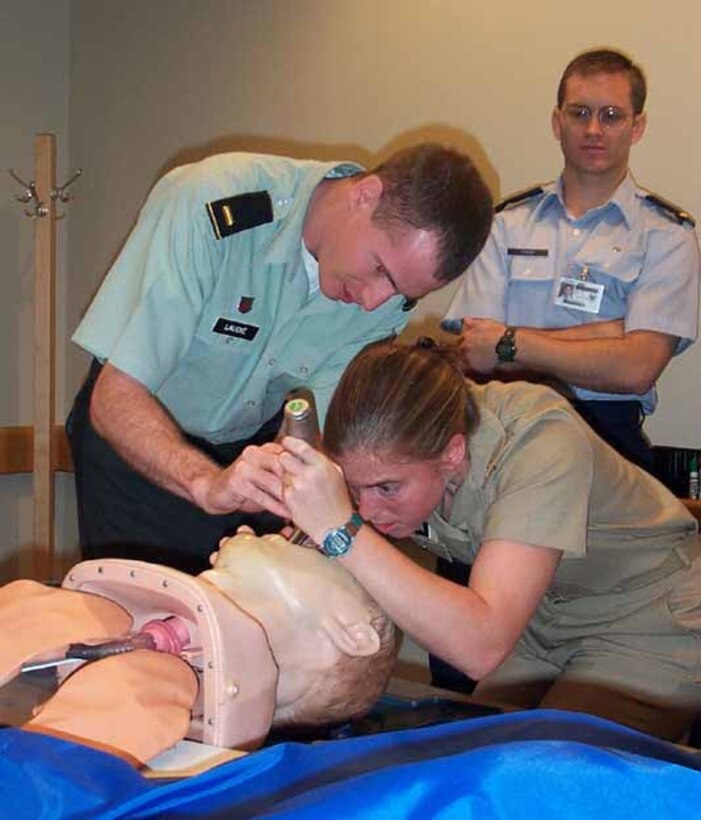 Navy Ensign Lisa A. Peterson, 25, checks the throat of a mannequin patient simulator with the help of Army 2nd Lt. Matthew Laudie. Air Force 2nd Lt. Jared Chugg watches the procedure. The three are training in the mock operating room of a virtual reality lab at the National Capital Area Medical Simulation Center, Walter Reed Army Medical Center Annex, in Forest Glen, Md. They're third- year medical students of the Uniformed Services University of the Health Sciences in nearby Bethesda, Md. Photo by Rudi Williams. 