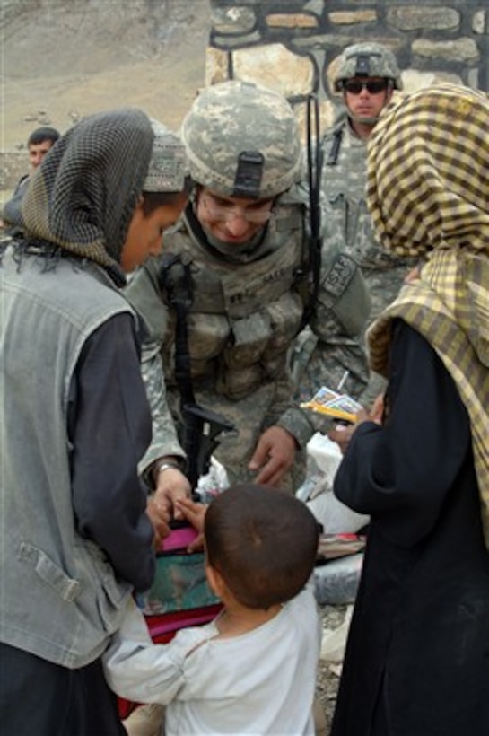 U.S. Air Force Capt. Erik Saks gives school supplies and humanitarian assistance to children as they leave after being seen by medical personnel during a medical civic action program in the district of Tagab in the Kapisa province of Afghanistan on April 30, 2007.  Saks is assigned to the Bagram Provincial Reconstruction Team.  