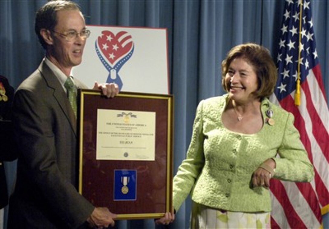 Dr. David Chu, under secretary of defense for personnel and readiness, presents the Office of the Secretary of Defense Award for Exceptional Public Service to co-founder of RE/MAX International, Gail liniger, for their support of armed forces.  