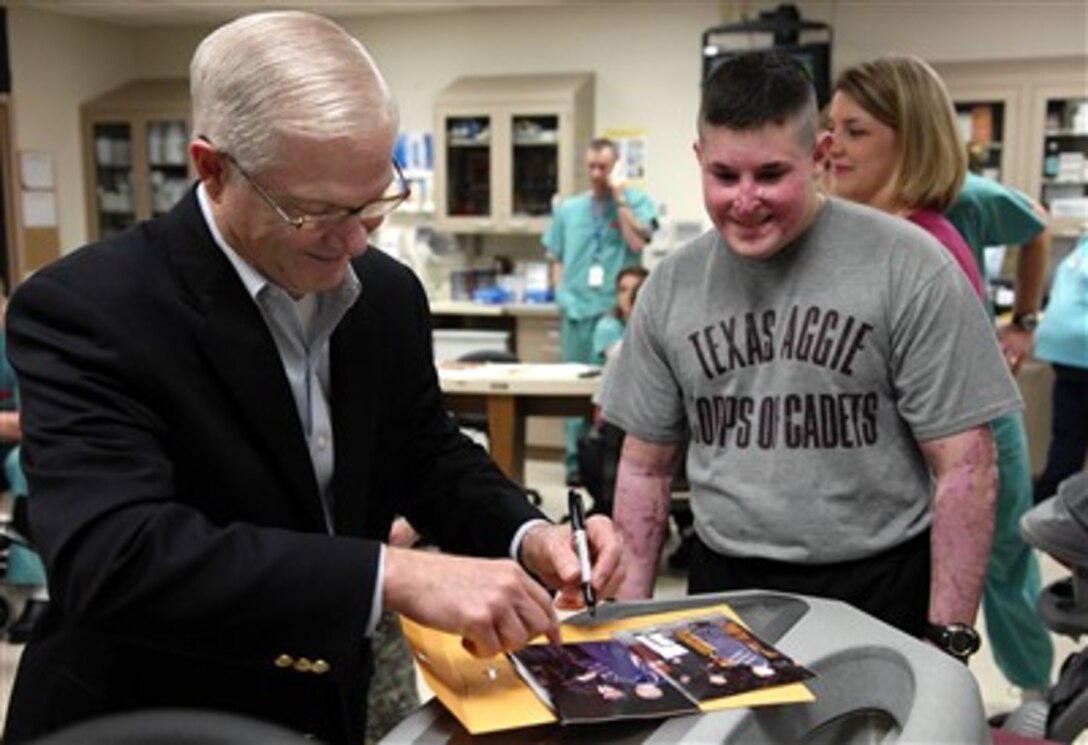 Defense Secretary Robert M. Gates signs a graduation photo for a former Texas A&M University graduate during a tour of the burn rehab center at Brooke Army Medical Center in San Antonio, Texas, May 4, 2007.  