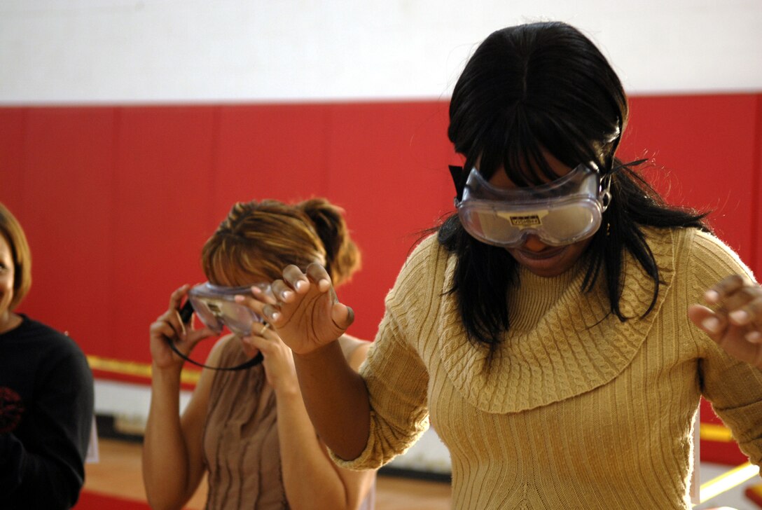 Lauren Clements, a 4-year military spouse, attempts to walk in a straight line while wearing goggles that simulate intoxication. Spouses were offered classes during the event on how to overcome problems they may face while their Marines are away from home.