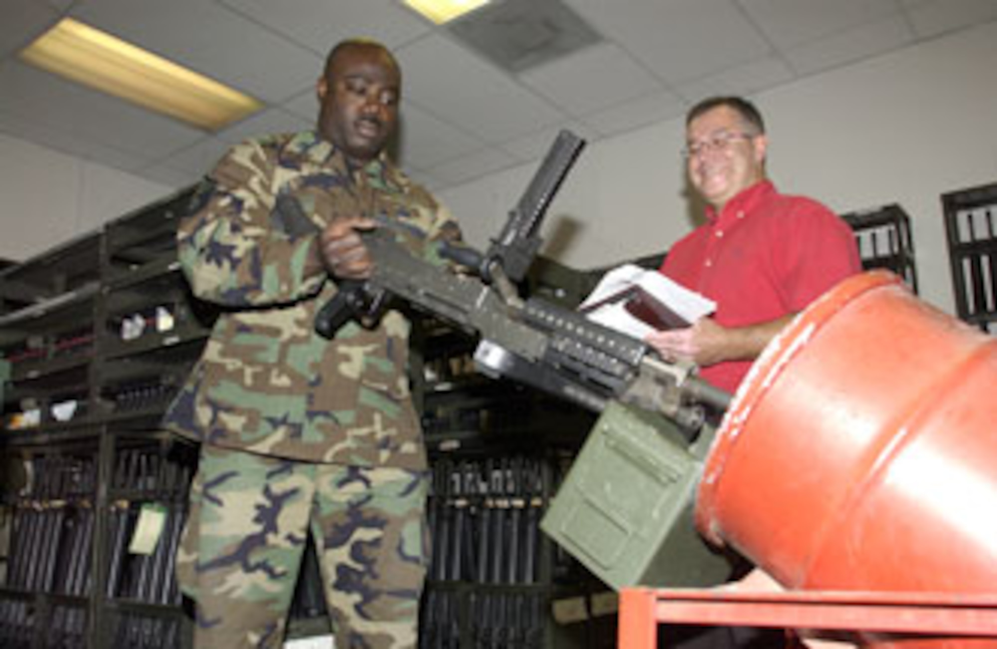 Vic Flores (right) observes as Master Sgt. Derrick Adkins, 452nd Security Forces armory noncommissioned officer in charge at March Air Reserve Base, demonstrates clearing procedures on one of the M240B machine guns in the inventory. (U.S. Air Force photo by Staff Sgt. Amy Abbott, 452 AMW/PA)