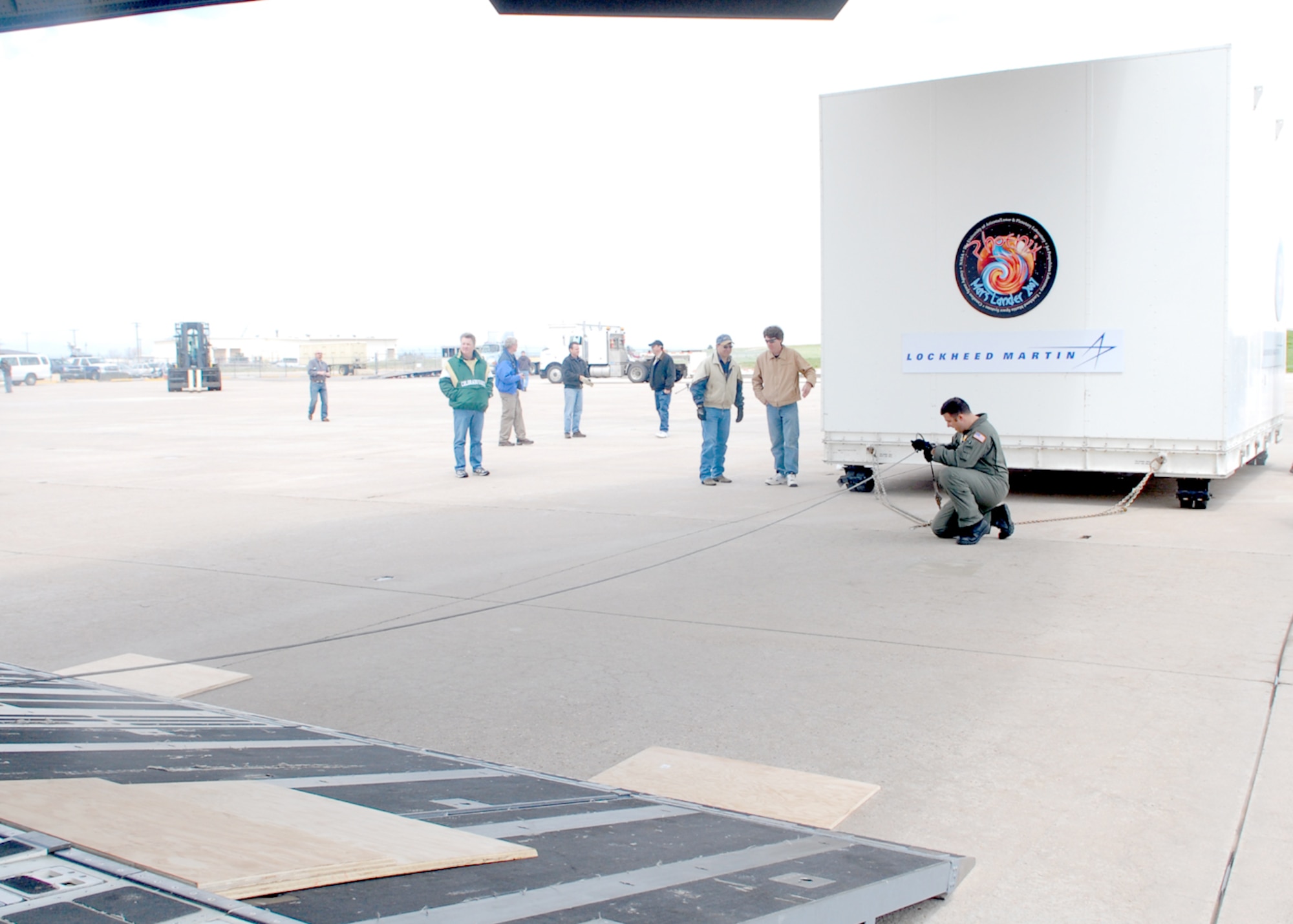 BUCKLEY AIR FORCE BASE, Colo. -- Staff Sgt. Mike Morris, a loadmaster with the 16th Airlift Squadron from Charleston Air Force Base, S.C., secures a cable to the transportation container holding NASA's Phoenix Mars Lander here May 7. The lander, which was built at Lockheed Martin Space Systems Company's Waterton Canyon facilities in Littleton, Colo., was loaded on a C-17 for transportation to NASA's Kennedy Space Center in Florida for final test and launch preparations. The Phoenix lander is slated for liftoff aboard a Delta II launch vehicle in early August. 

Phoenix is the first mission of NASA's Mars Scout Program. The spacecraft will land on the icy northern latitudes of Mars. During its approximately 90-day mission, Phoenix will dig trenches with its robotic arm into the frozen layers of water below the surface. The spacecraft will use various on-board instruments to analyze the contents of the ice and soil; all in the hopes of finding organic compounds that are necessary for life. (U.S. Air Force photo by Airman 1st Class Alex Gochnour)
