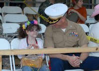 Marine Col. Marc Magram, director of the Joint Electronic Warfare Center at Lackland, admires a Fiesta medal given to his daughter Lexi prior to the April 28 start of the 60th annual Fiesta Flambeau Parade through downtown San Antonio. Lexi and her dad were two of an estimated 500,000 spectators for what has been called the nation's largest illuminated night parade. (USAF photo by Alan Boedeker)
