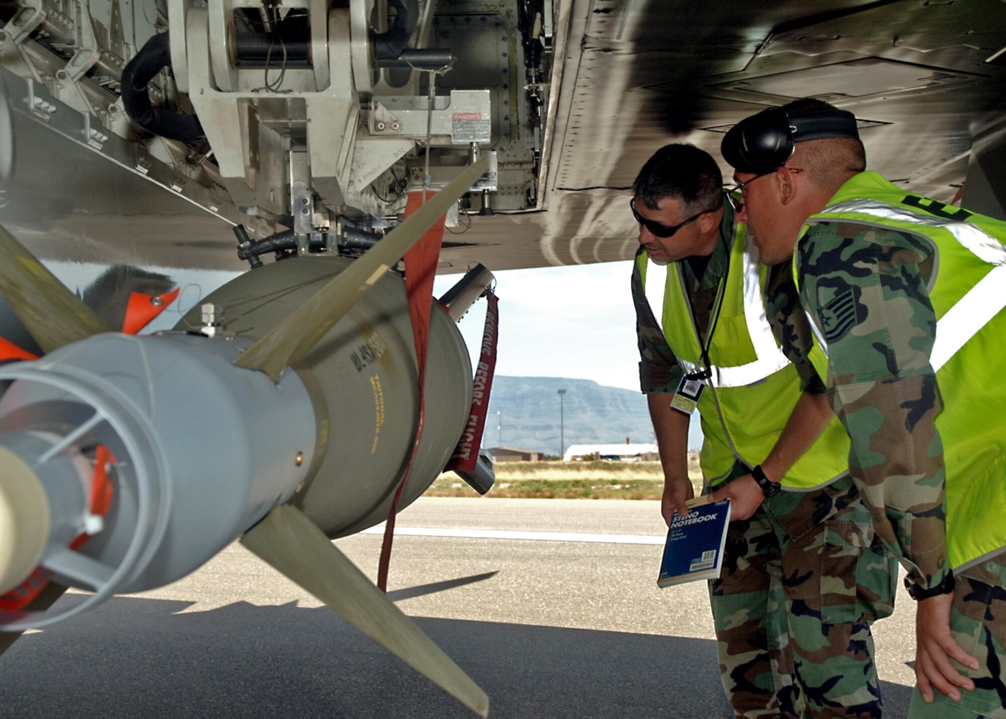 Tech. Sgt. Kirtus Fisher and Master Sergeant Jim Jelly, both from the 49th Aircraft Maintenance Squadron, inspect the loading of a GBU-10 onto an F-117A at Holloman. (United States Air Force photo by Airman 1st Class Tiffany Mayo)