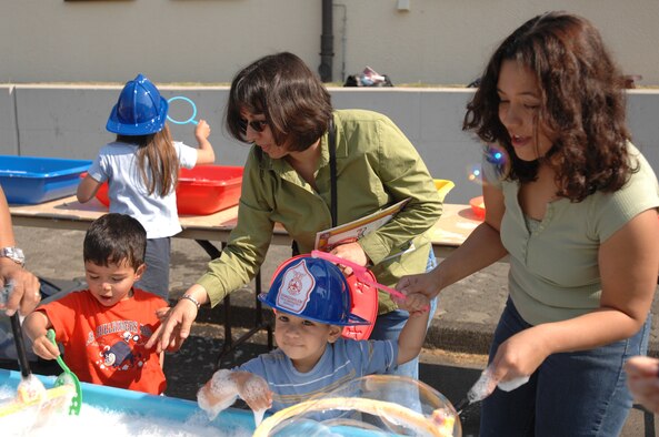 SPANGDAHLEM AIR BASE, GERMANY -- Yvonne Garza, far right, and her son, John, 2, played with giant bubbles during the Month of the Military Child Block Party at the fitness center April 28. Several parents and more than 500 kids attended. A variety of events were offered, a fishing booth, temporary tattoos, arts and crafts, a bouncy castle, and more. The Green Knights Motorcycle Club sponsored a bicycle rodeo and inspected many of the kids bikes for safety. The Health and Wellness Center staff also held several fitness events for the kids. Additional activities included a magician and cheerleader performance. The 52nd Dental Squadron hosted a dental awareness booth, and students participating in the National History competition in June hosted a display of their winning projects. (US Air Force photo/Airman 1st Class Emily Moore)