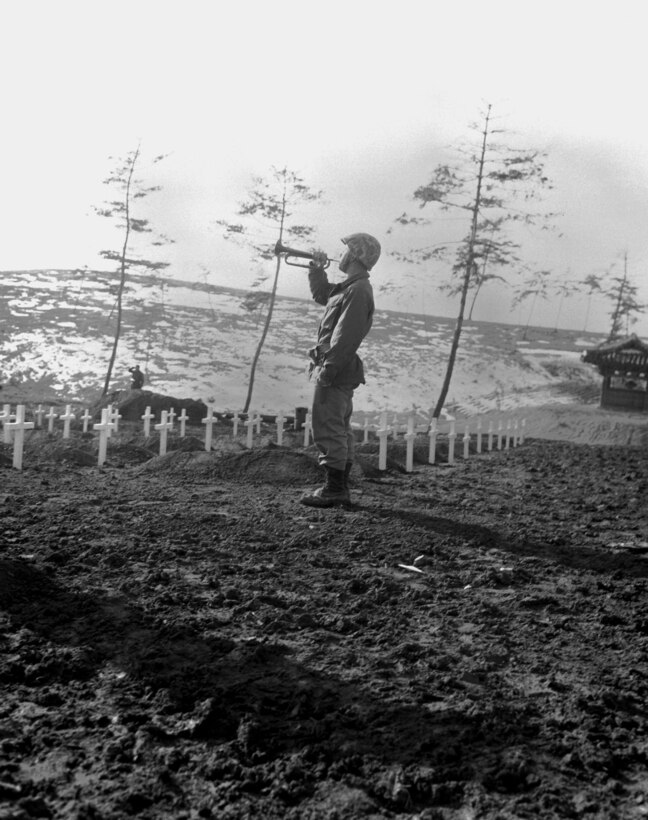 Marine Cpl. Charles E. Price sounds "Taps" over the graves of fallen Leathernecks during memorial services Dec. 13, 1950, at the 1st Marine Division cemetery at Hungnam, Korea, following the division's break-out from the Chosin Reservoir. DoD Photo by Cpl. W.T. Wolfe, USMC.