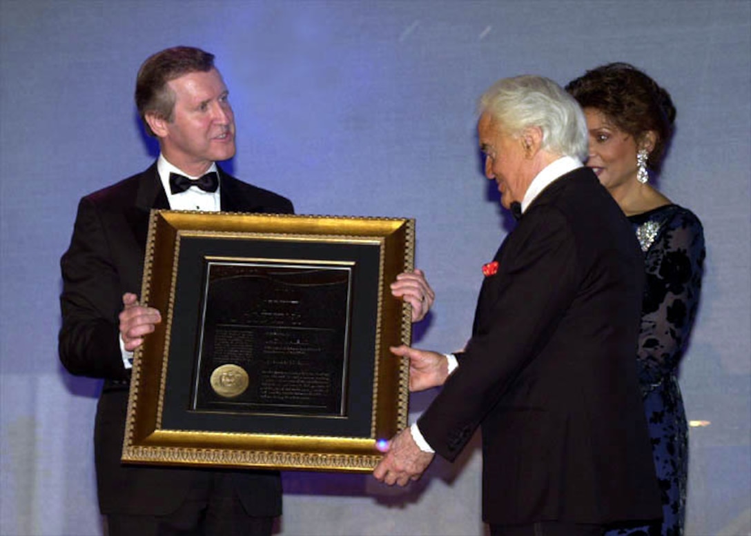 Defense Secretary William S. Cohen (left), presents DoD's first Citizen Patriot Award to Jack Valenti, president of the Motion picture Association of America, while Janet Langhart Cohen looks on. Cohen honored Valenti for his World War II service and his efforts to promote a positive military image within the film industry. Air Force Photo by Lou Hernandez. 