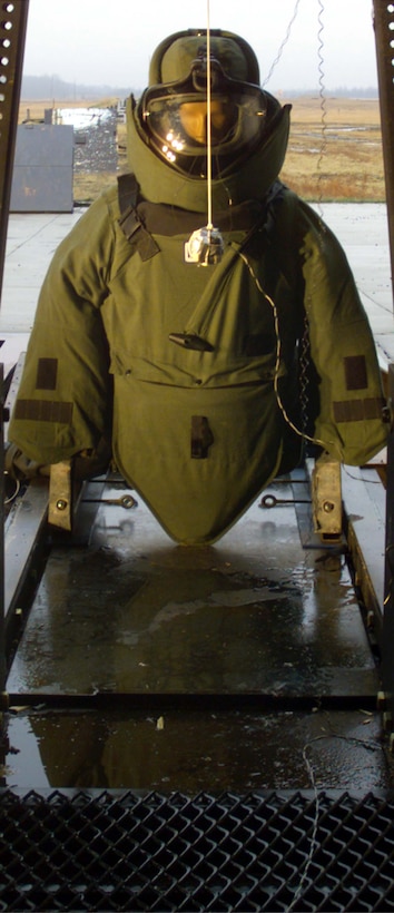 An explosive charge hangs in front of a test dummy wearing a concept protective bomb suit at Aberdeen Proving Ground, Md. The manikin is equipped with sensors that will allow engineers to measure blast effects on the suit and its wearer. 
