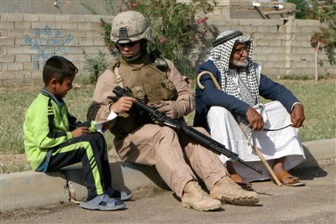 U.S. Marine Corps Sgt. Andrew Morris shows an Iraqi boy how to write in English as they sit on a curb in Al Fahren, Iraq, on April 16, 2007.  Morris and his fellow Marines from 2nd Battalion, 10th Marine Regiment, are visiting Al Fahren to assist the citizens with medical and other issues they are experiencing.  