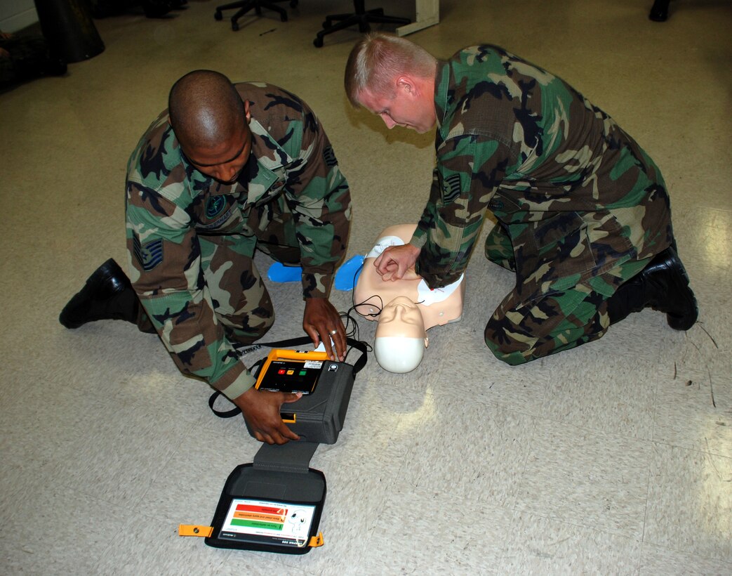 Tech. Sgt. James Eberheart checks the automated external defibrillator as Tech. Sgt. Robert Rogers applies chest compressions to a practice dummy during the Severe Weather Response Excercise. The AED has been credited in recent months with saving the lives of two Team Sheppard members. (U.S. Air Force photo/Airman 1st Class Jacob Corbin)
