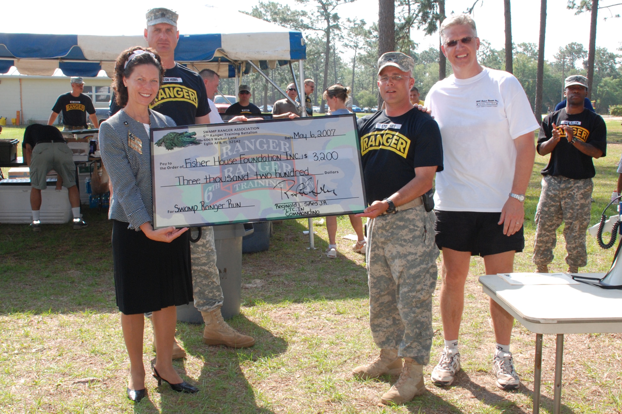 CAMP RUDDER, Fla. -- Trecia Chedister accepts a check from U.S. Army Lt. Col. Lee Sikes for $3,200 on behalf of the Emerald Coast Fisher House Foundation from the proceeds of more than 250 runners at the first of an annually planned five-kilometer and 10-kilometer run at the 6th Ranger Training Battalion Ranger Open House May 6. At final count, more than $4,000 was raised from the race and the Open House and donated to the Fisher House. Colonel Sikes is the 6th RTB commander. (U.S. Air Force photo by Staff Sgt. Mike Meares)