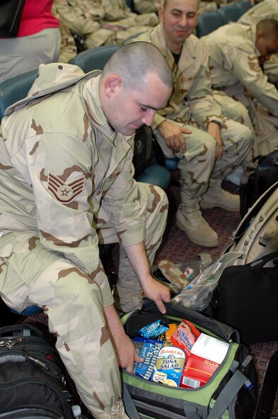 Staff Sgt. Kenneth Gately, 60th Diagnostics and Therapeutic Squadron, repacks his overnight snack bag while waiting to board the aircraft May 5. Sergeant Gately’s wife packed his bag with snacks so he would not get hungry during the long flight to the area of responsibility. (U.S. Air Force by Staff Sgt. Candy Knight) 