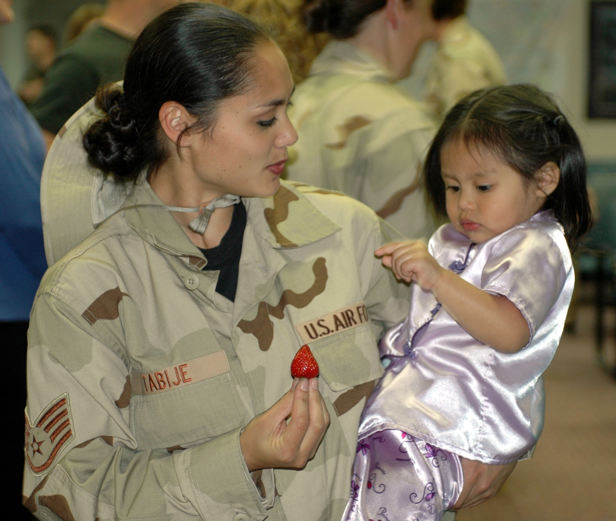 Staff Sgt. Carolyn Tabije, 60th Medical Operations Squadron, offers her daughter Lei Ling, 2, a strawberry at the Travis Passenger Terminal May 5. Sergeant Tabije, along with approximately 60 Team Travis members bid farewell to family and friends before departing as part of Air Expeditionary Force-cycles 7/8. (U.S. Air Force photo by Staff Sgt. Candy Knight)