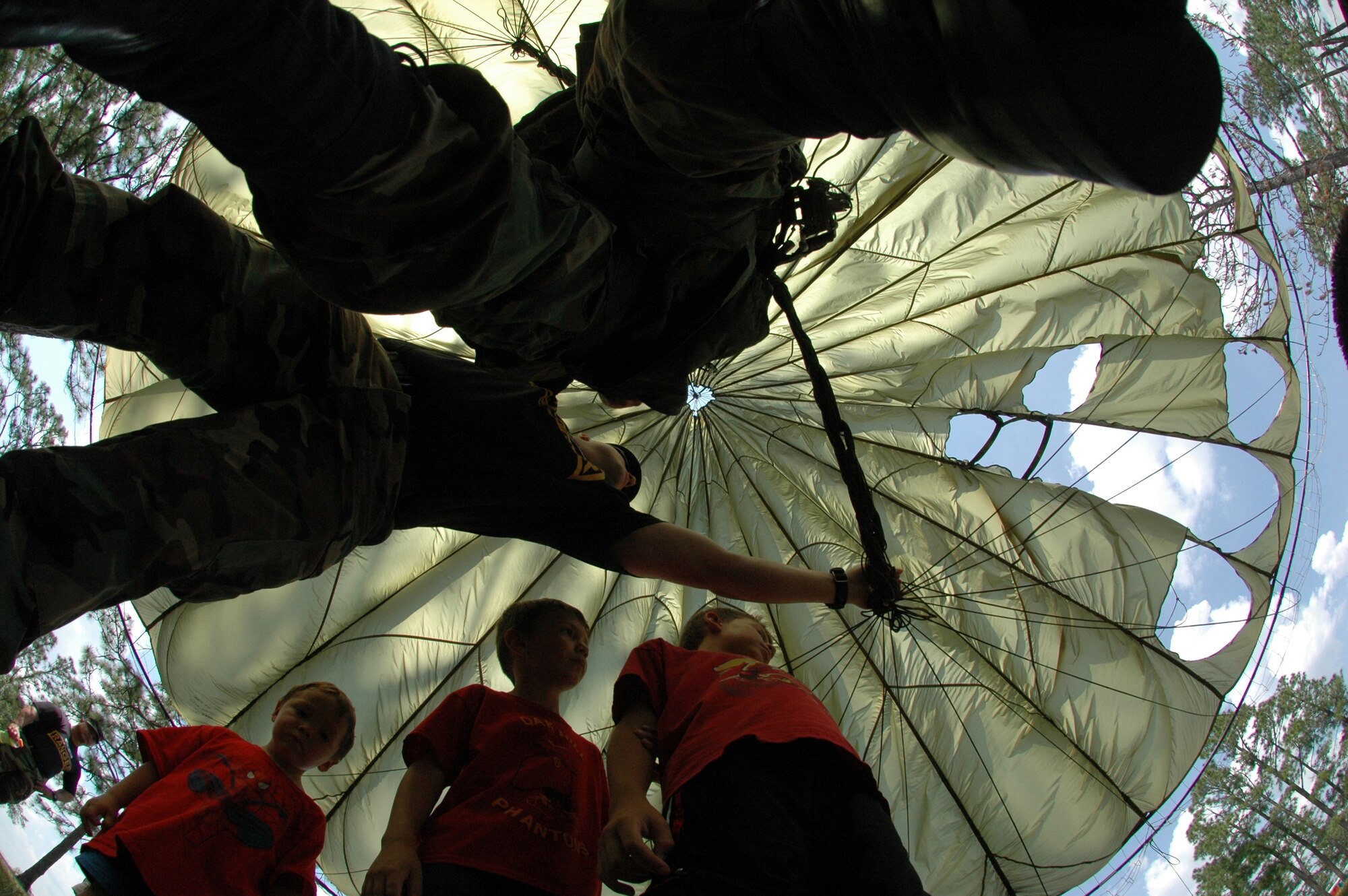 CAMP RUDDER, Fla. -- U.S. Army Staff Sgt. Brent Steinhaus, 6th Ranger Training Battalion instructor, shows Nick, Alex and Theo DeLeon how the parachutes the Army Rangers use works during the Ranger Open House May 6. "A largest crowd ever" of people of all ages visited the 6th RTB Rangers as they brought out their equipment for hands-on displays of weapons, diving equipment, Zodiac boat, parachute, medical and a day-in-the-life display for the Ranger training school. The Army's Reptile Team put on a reptile show where people took an up-close look at venomous and non-venomous snakes that could be found just feet from where the spectators were standing. They also put on repelling demonstrations, a downed pilot rescue demonstration and a hand-to-hand combat demonstration. (U.S. Air Force photo by Staff Sgt. Mike Meares)